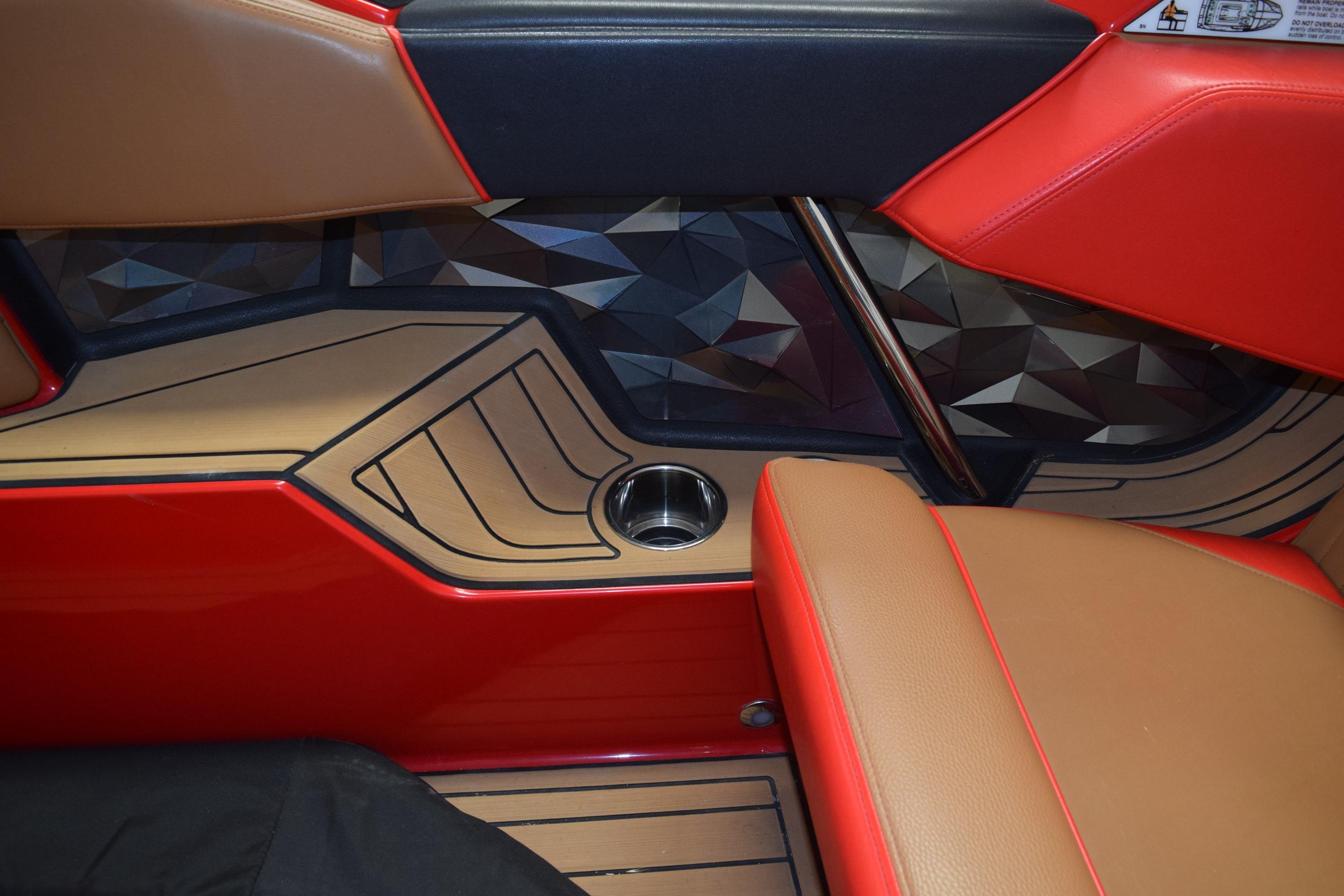 2024 Nautique Ski Nautique interior with red and tan seating, geometric paneling, and cup holder.