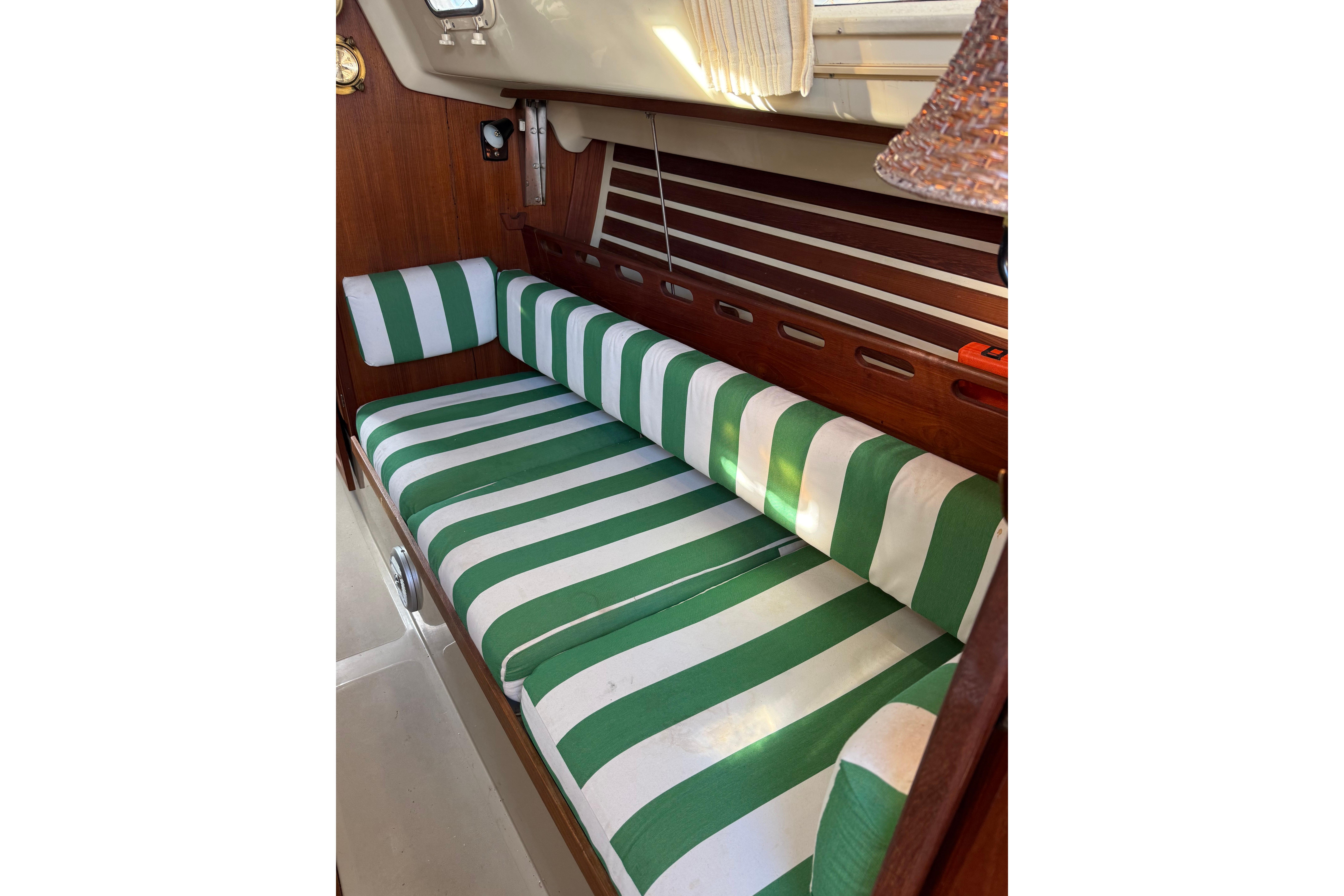 Green and white striped seating inside a 1983 O'Day 34 sailboat cabin.