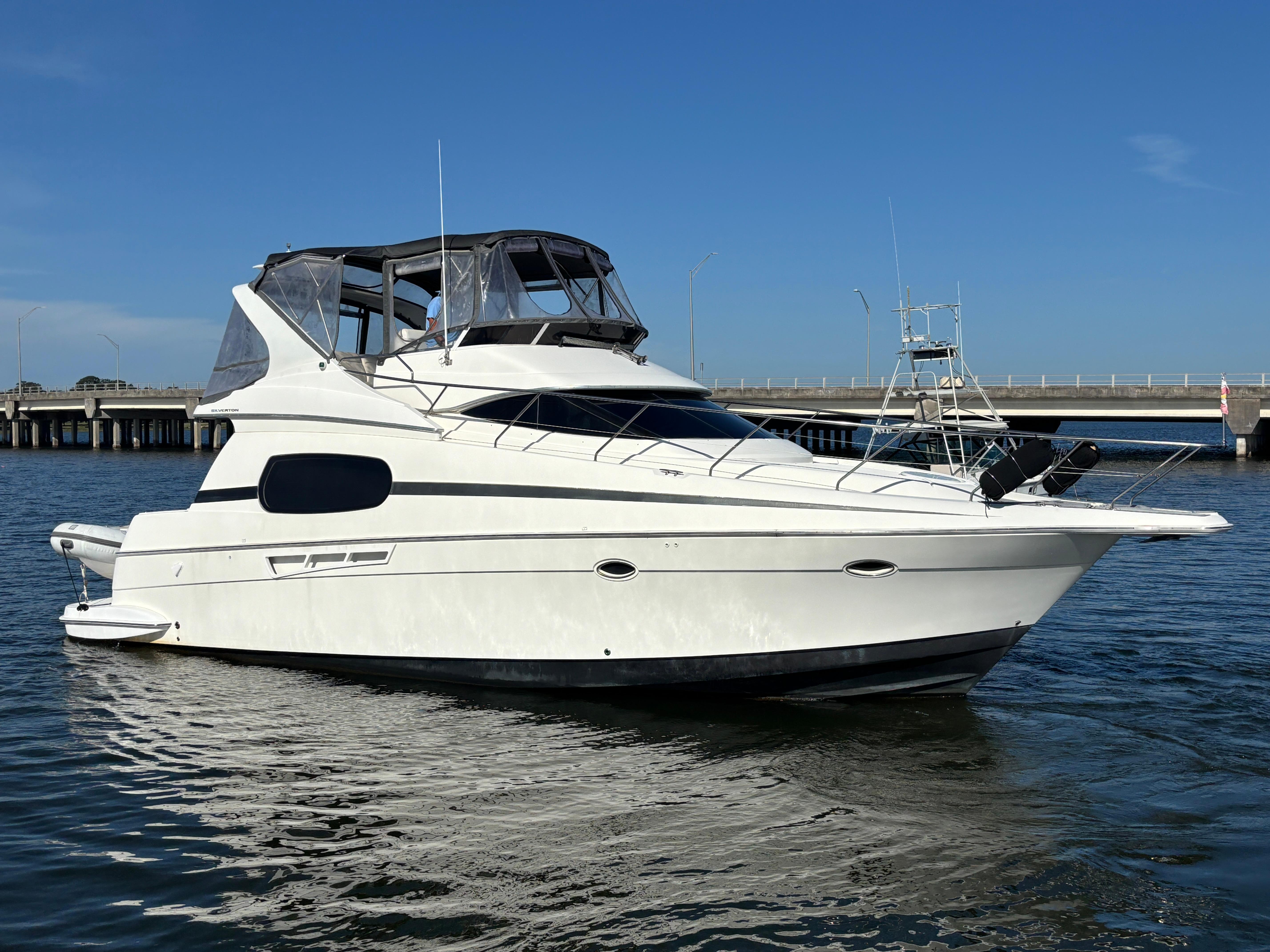 2001 Silverton 410 Sport Bridge yacht on calm water, with a clear blue sky background.