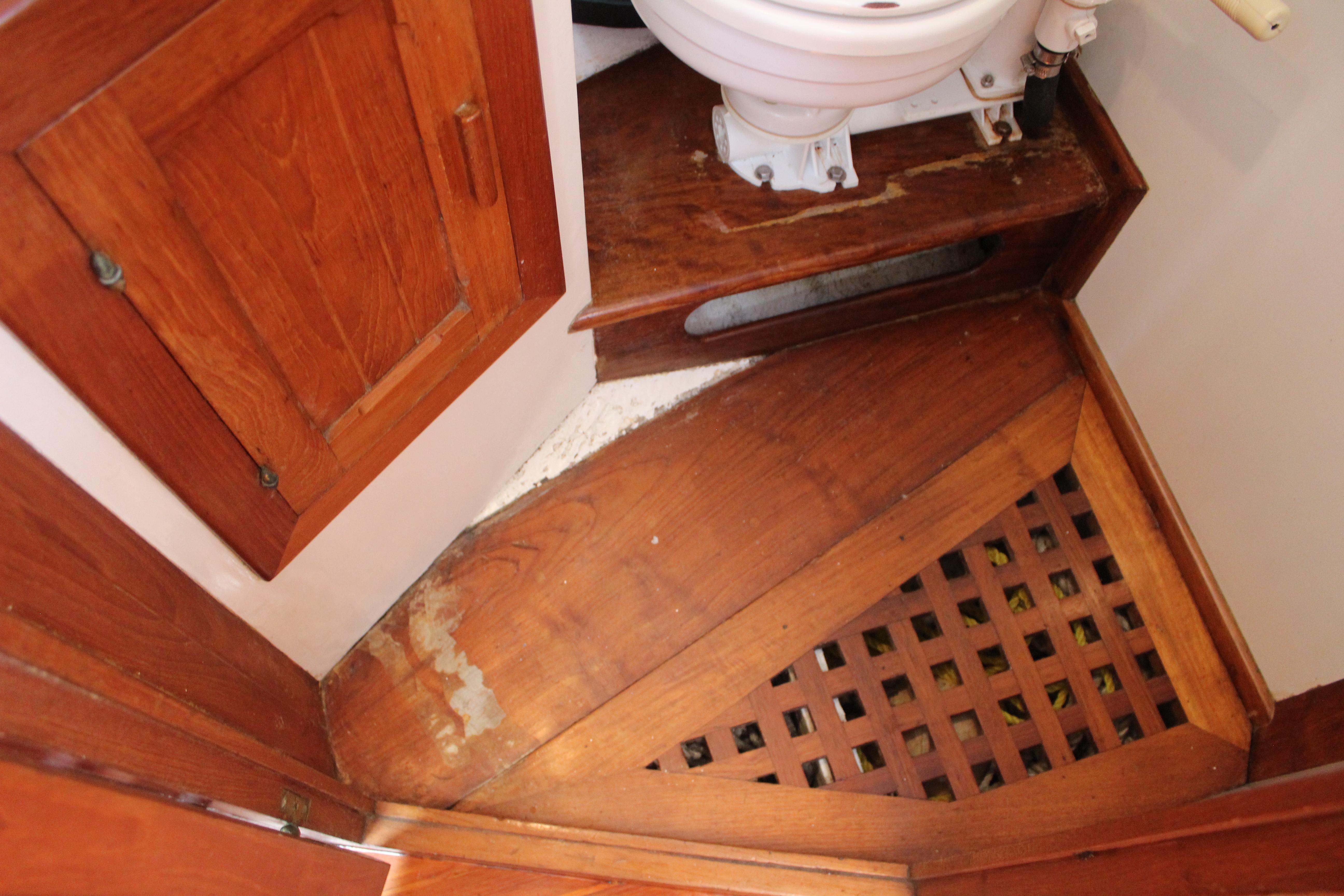 Wooden interior of 1981 Kelly Peterson 46 sailboat bathroom with toilet and storage.
