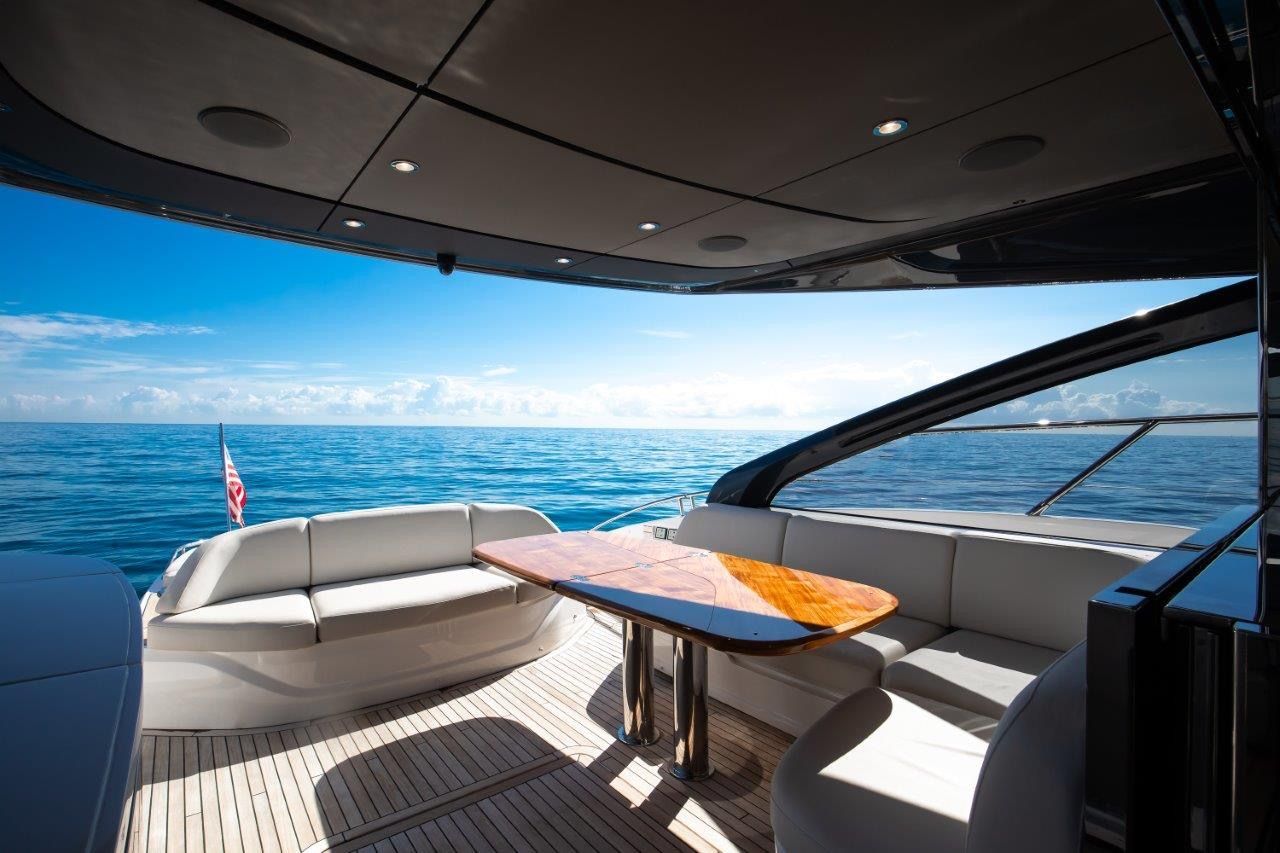 Luxurious deck of the 2025 Princess V55 yacht with elegant seating and a wooden table.