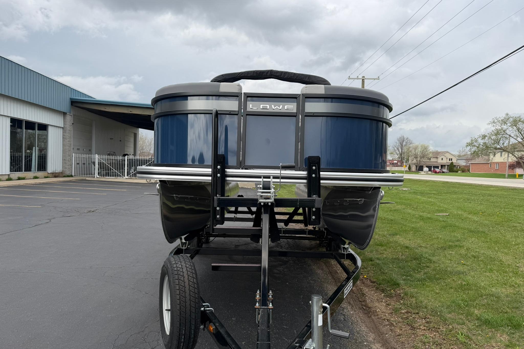 2026 Lowe LS 190 pontoon boat on trailer, parked outdoors near a building.