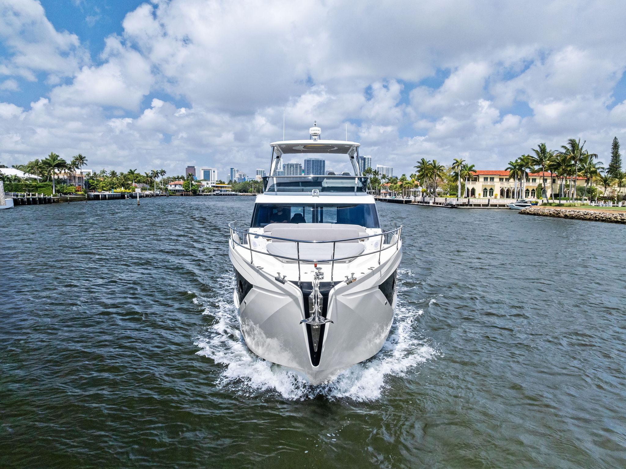 2023 Absolute 52 FLY yacht cruising on a scenic waterway under a partly cloudy sky.