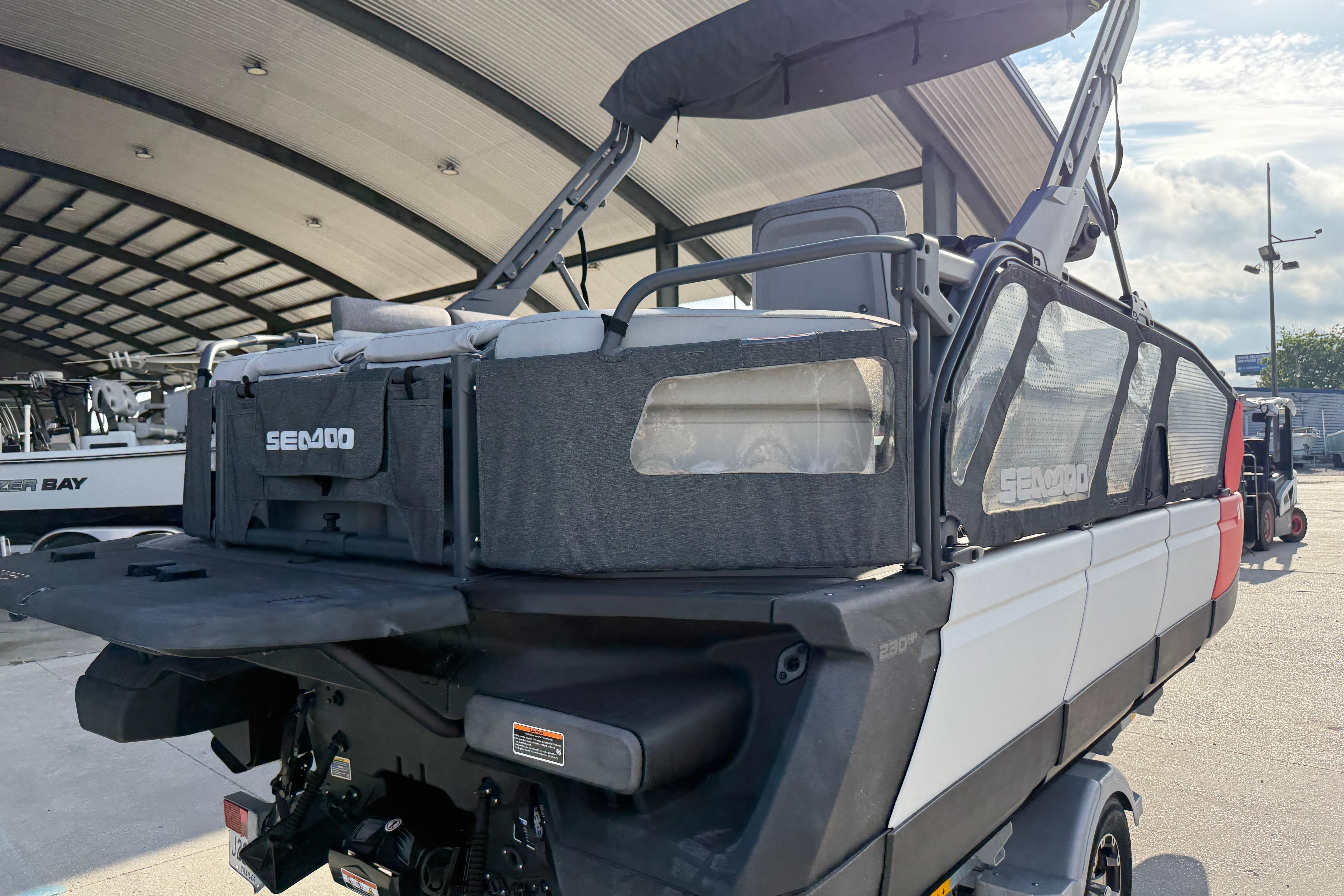 2023 Sea-Doo Switch Sport 18 pontoon boat with canopy, parked in a marina.