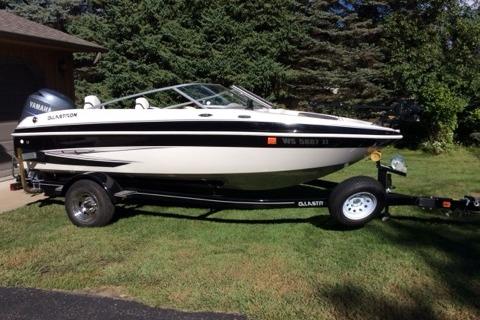 2012 Glastron GT180 boat on trailer, parked on grass near trees.