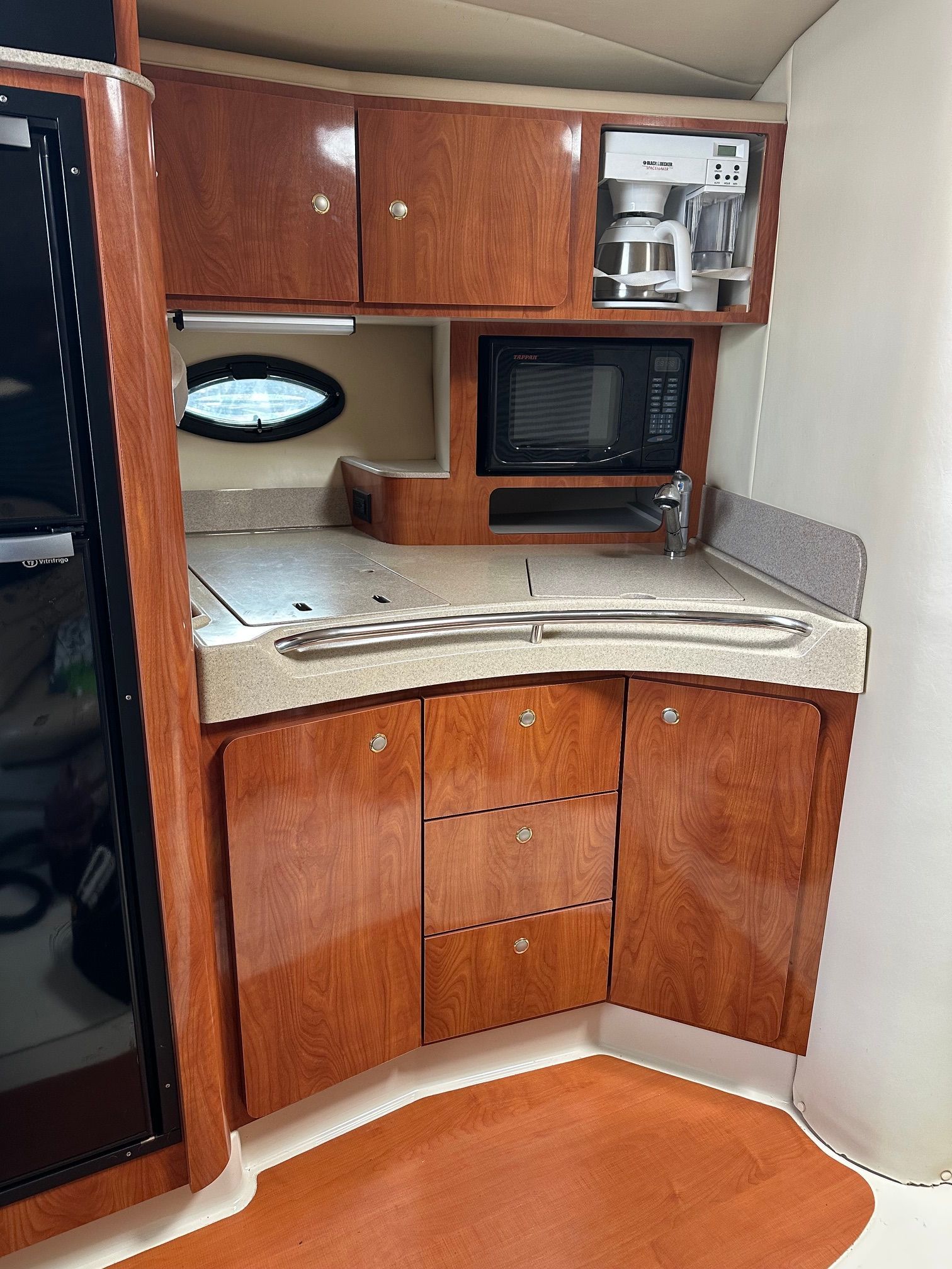 Galley area with wooden cabinets, microwave, and coffee maker in a boat.