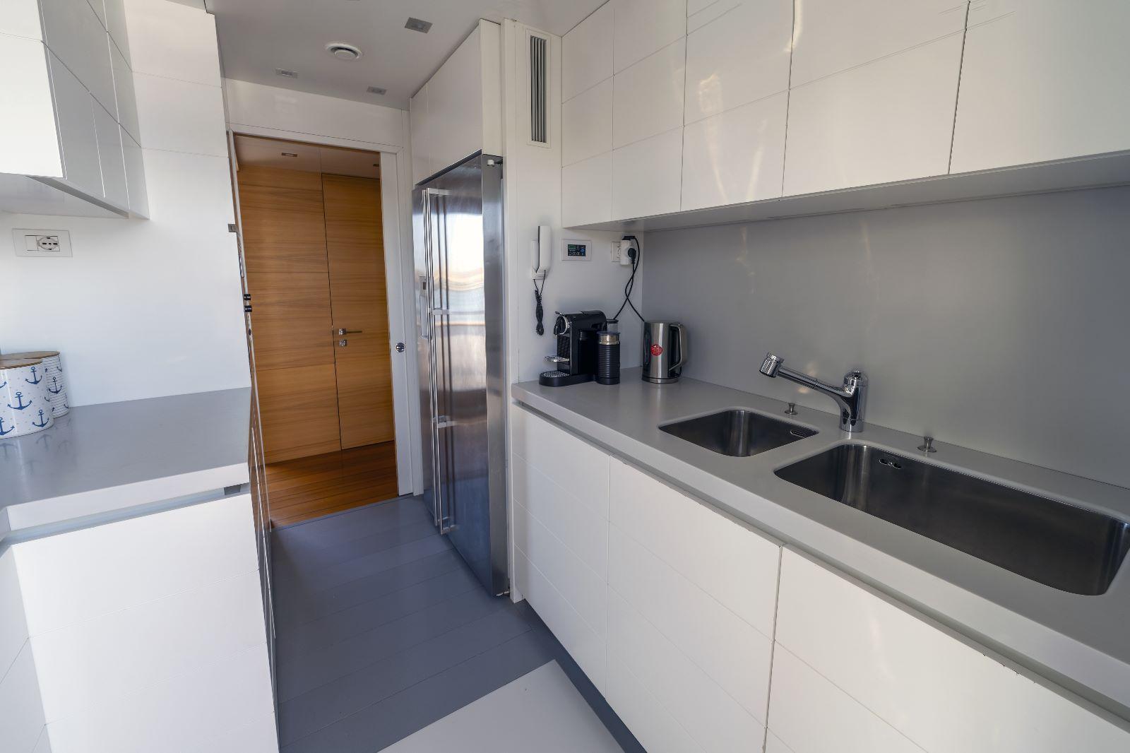 Modern kitchen interior on 2011 Maiora 27 yacht, featuring sleek white cabinetry and dual sinks.