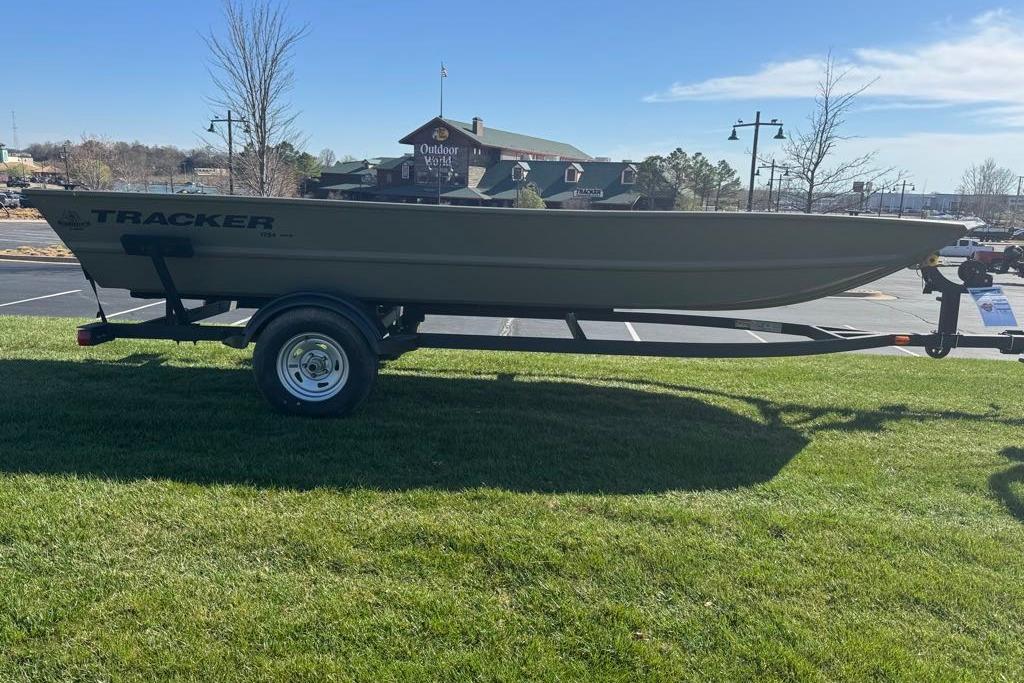 2026 Tracker Grizzly 1754 Utility boat on trailer, parked on grass near outdoor store.