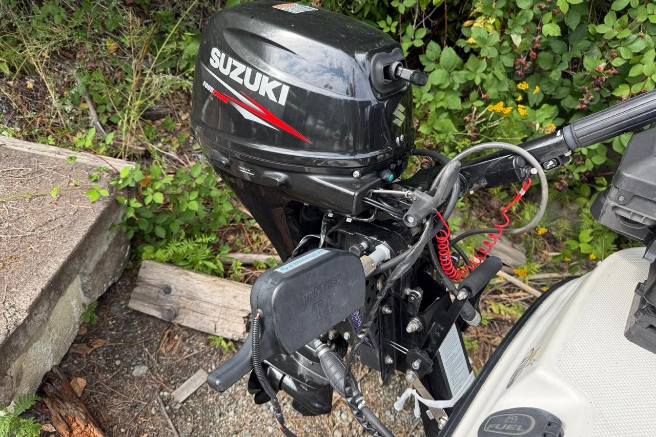 Outboard motor on a 2005 Bayliner 210 Discovery, surrounded by greenery.