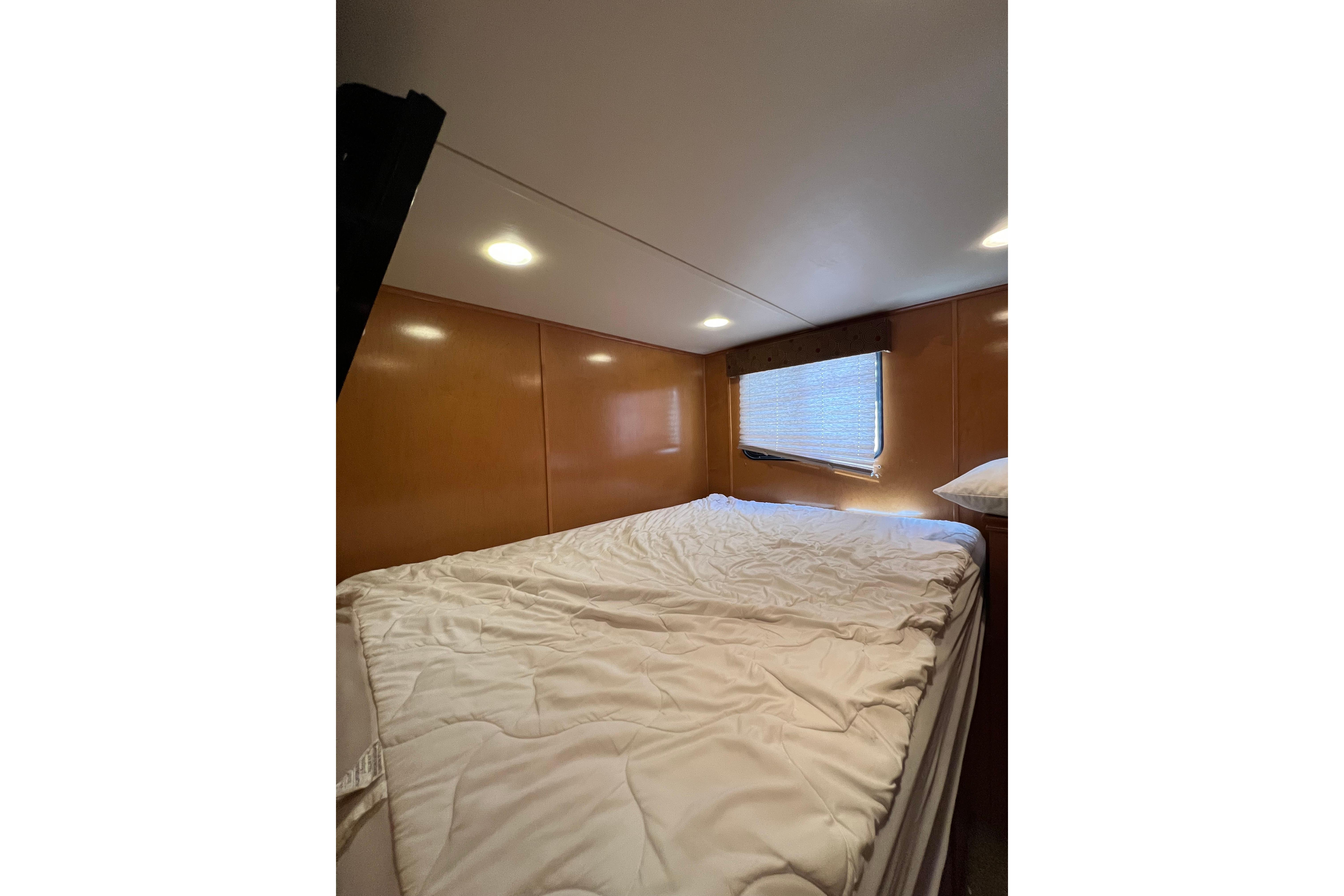 Cozy bedroom interior of 2013 Destination Yacht Lotta Yachta with soft lighting and window.