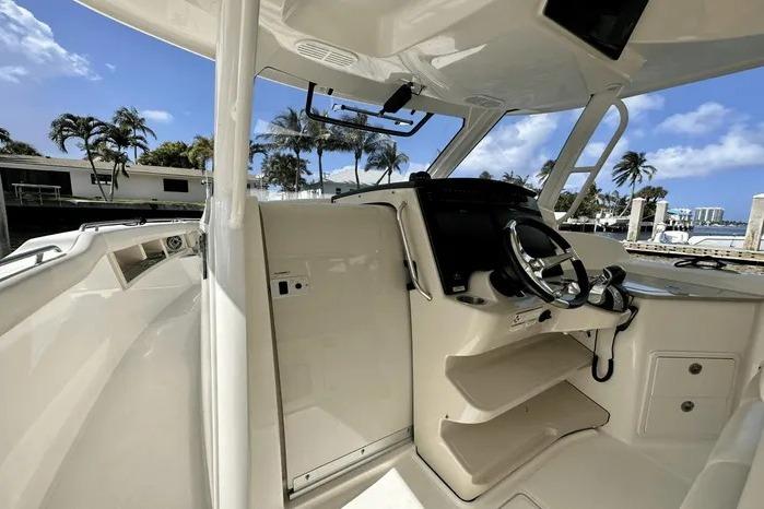 2019 Boston Whaler 350 Realm helm with steering wheel, tropical marina backdrop.