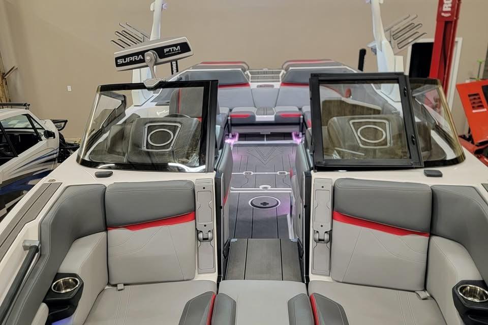 2023 Supra SE 550 boat interior with gray and red seating, open windshield, and modern design.
