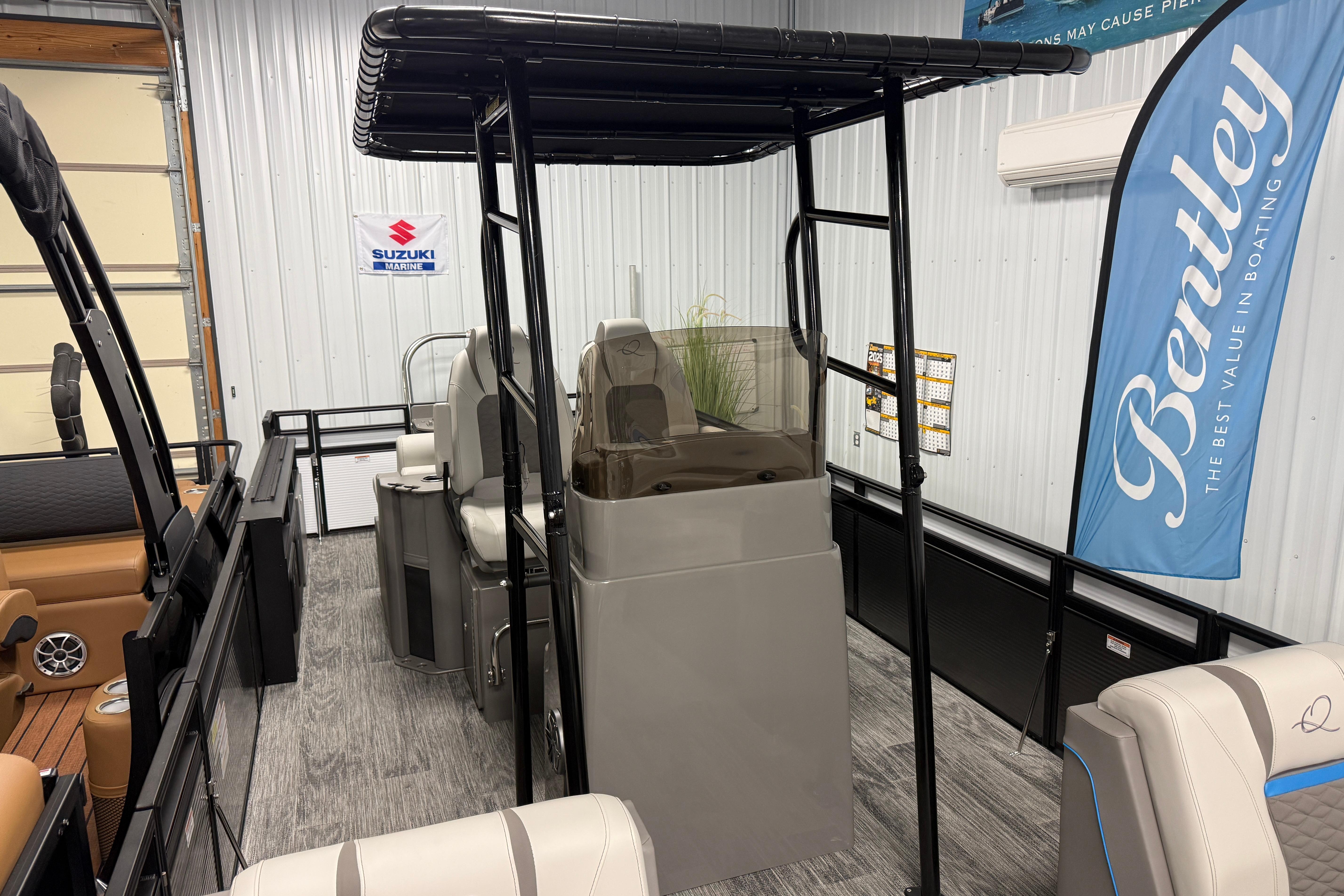 2026 Qwest M-Class 22 Pro Sport boat interior with seating and canopy in showroom.