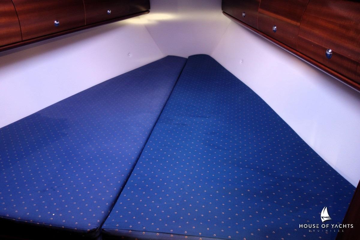 Cozy cabin interior of 2003 Bavaria 32 yacht with blue bedding and wooden cabinets.