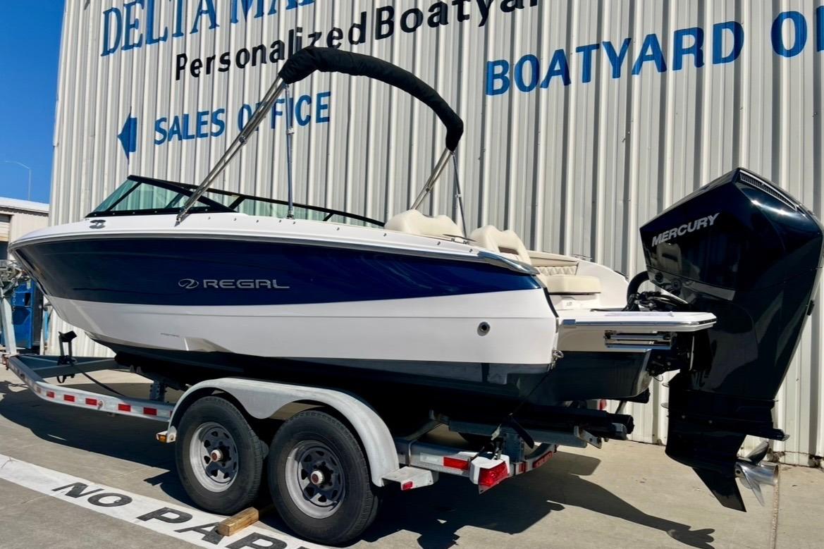 2025 Regal LX2 boat on trailer, displayed outside dealership with Mercury engine.