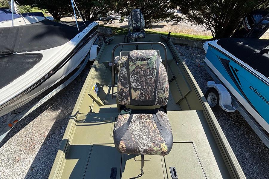 2022 Lowe Roughneck 1660 boat with camouflage seating, parked between other boats.