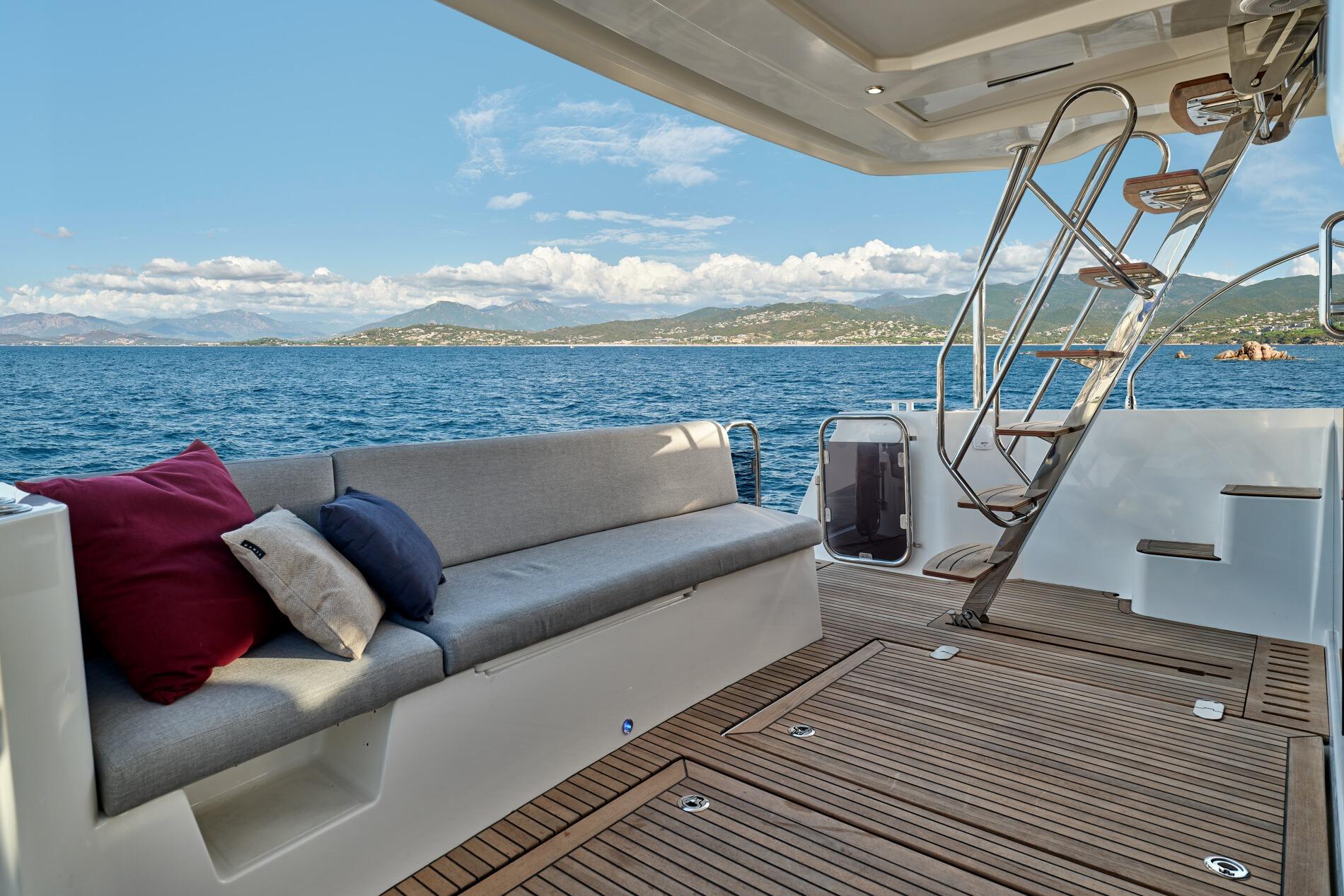 2026 Beneteau Swift Trawler 48 deck with seating, ocean view, and stairs.