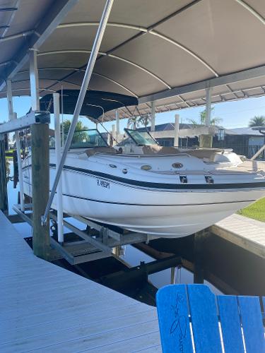 2015 Hurricane SunDeck 2400 OB boat docked under a canopy.