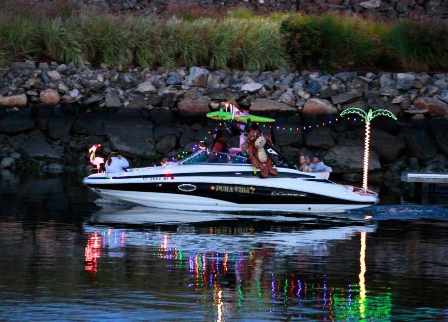 A 2013 Crownline E-4 Bowrider decorated with lights and ornaments, cruising on the water.