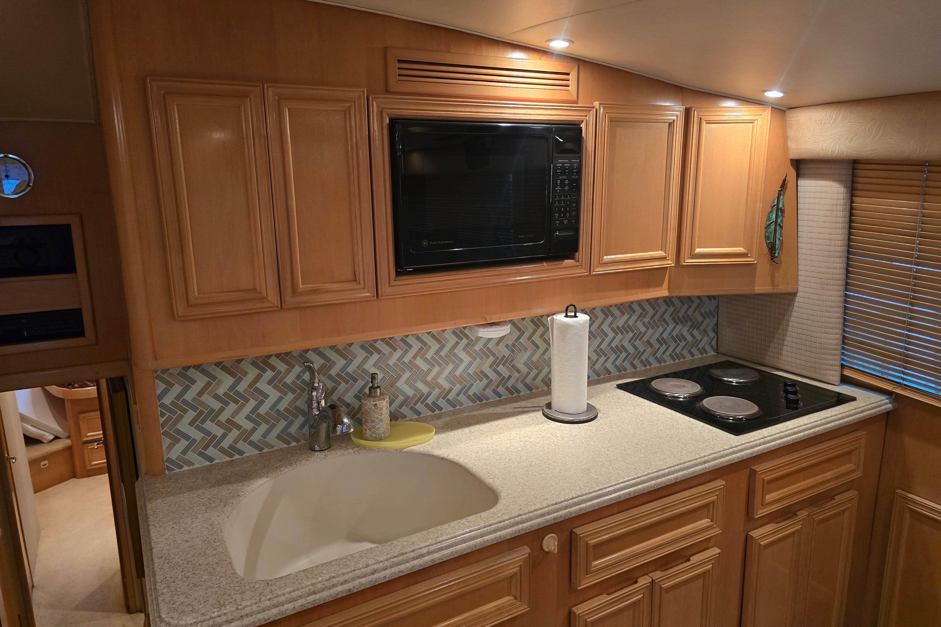 2001 Cavileer 53 Convertible yacht kitchen with wooden cabinets, microwave, and stovetop.