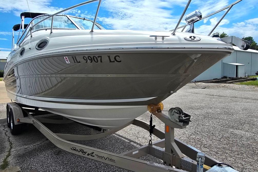 2006 Sea Ray 240 Sundancer boat on trailer, parked outdoors under a clear blue sky.