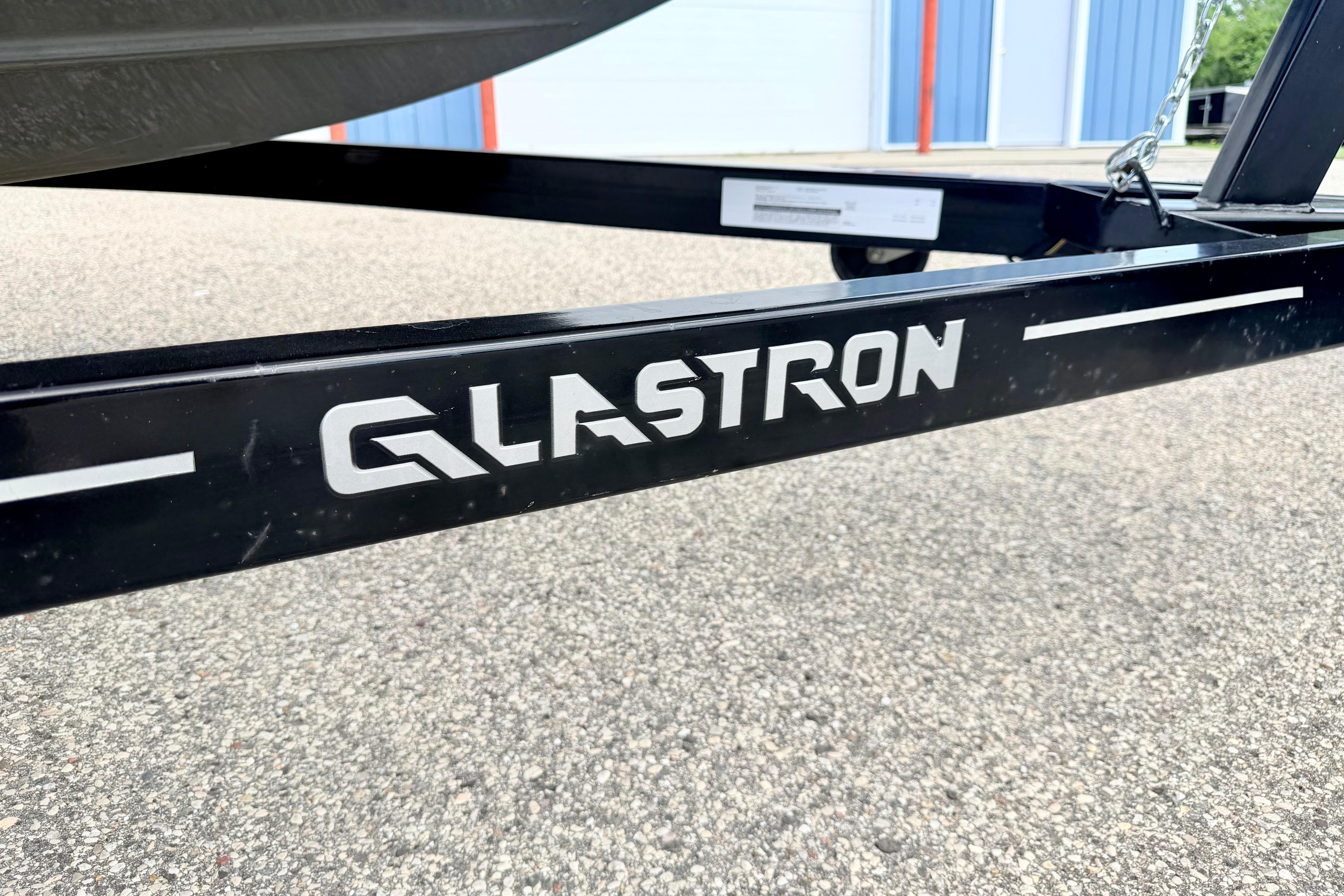 Trailer of 2018 Glastron GT 185 boat on pavement background.