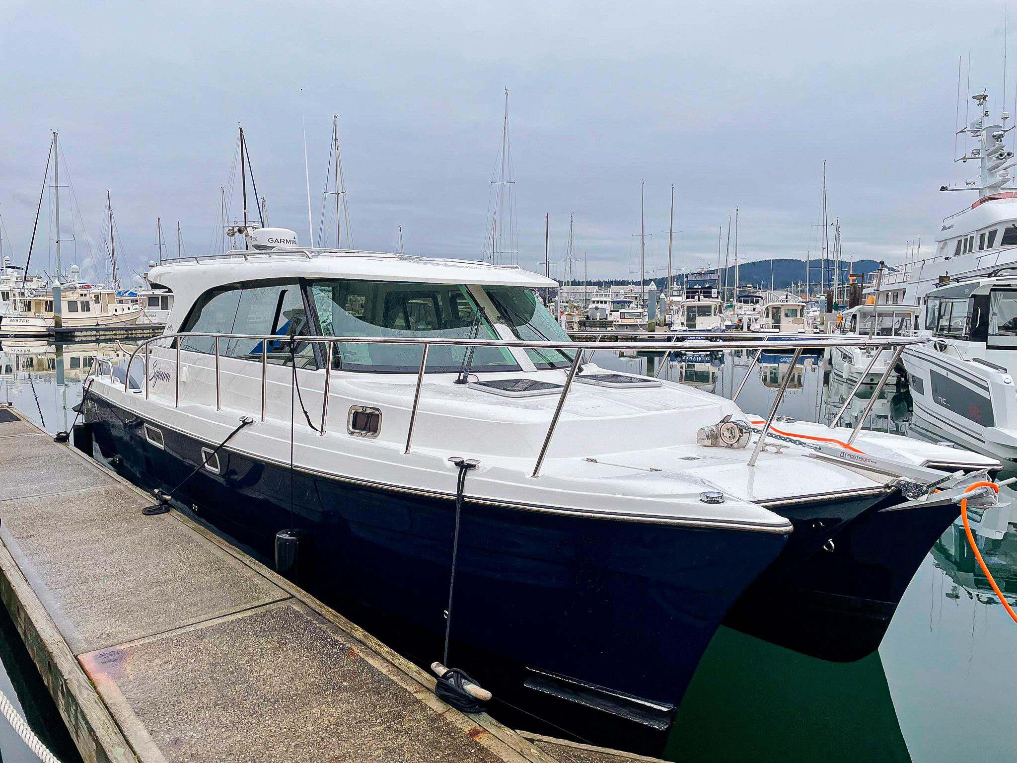 2026 Aspen C108 yacht docked at marina with sailboats in background.