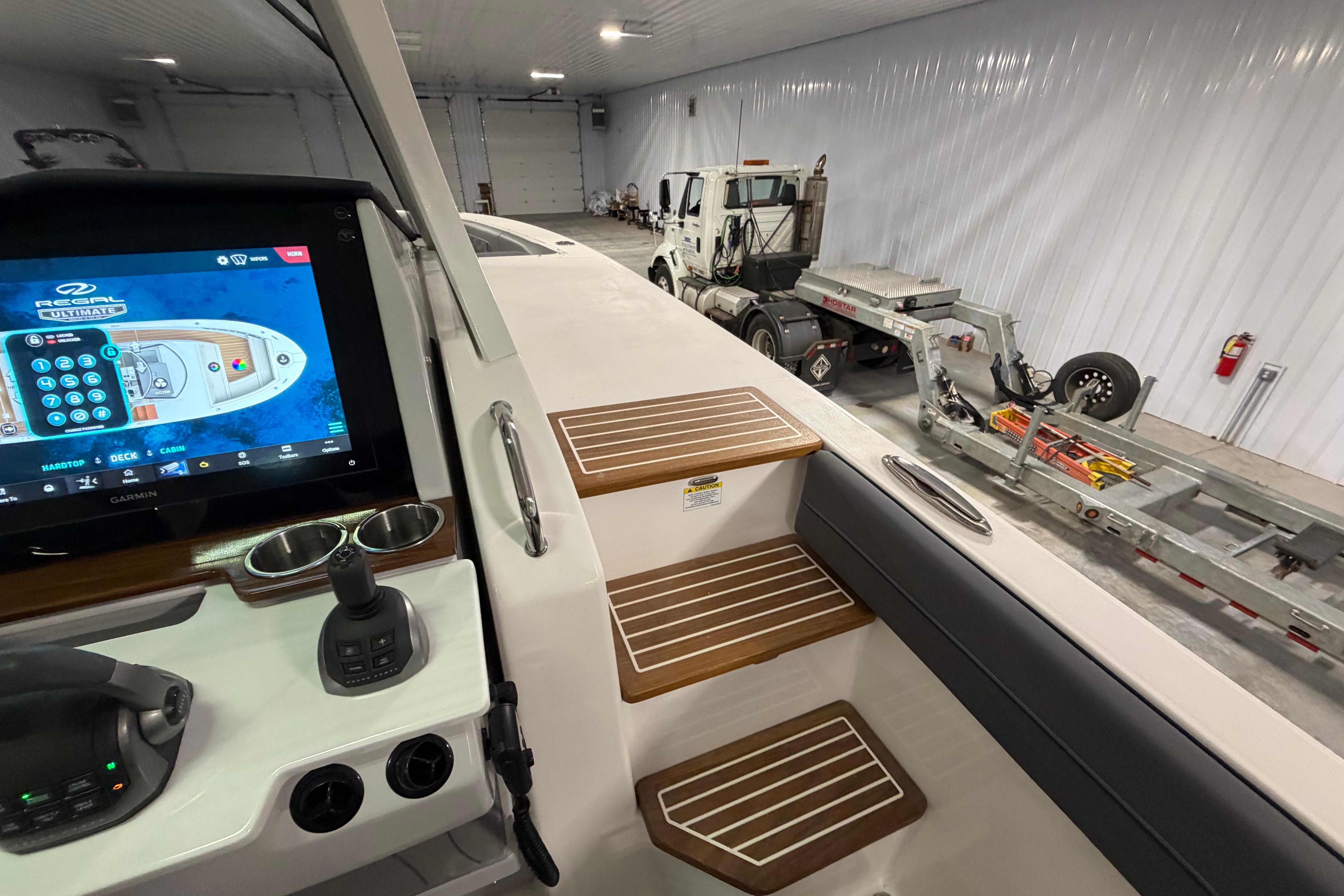 2027 Regal 38 Surf boat interior with control panel and wooden steps in a garage.