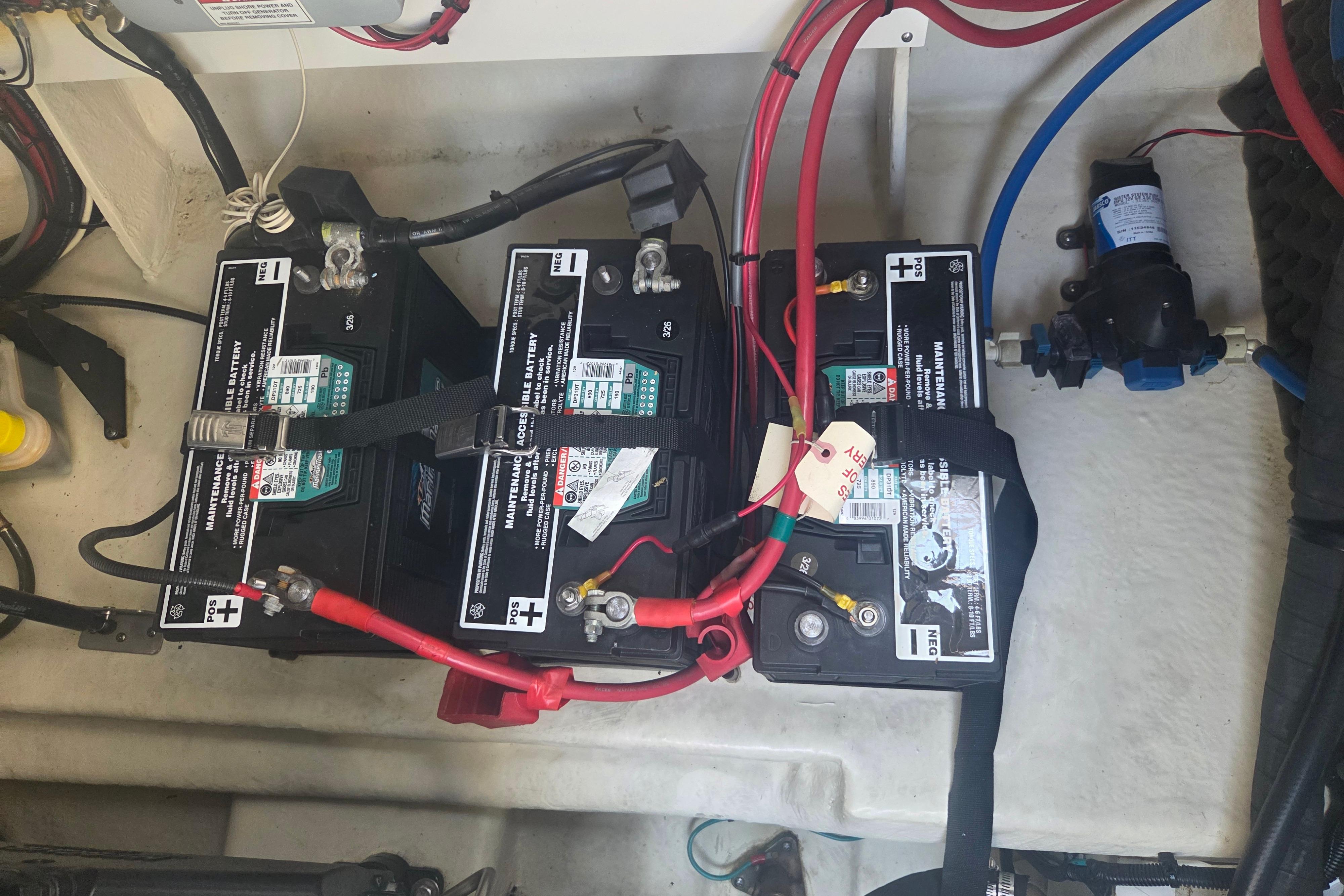Battery compartment of a 2012 Sea Ray Sundancer 260 boat, showing three connected batteries.