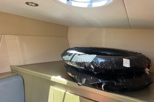 Interior of 2024 Bracewell 25 boat with stacked black tires on wooden surface.