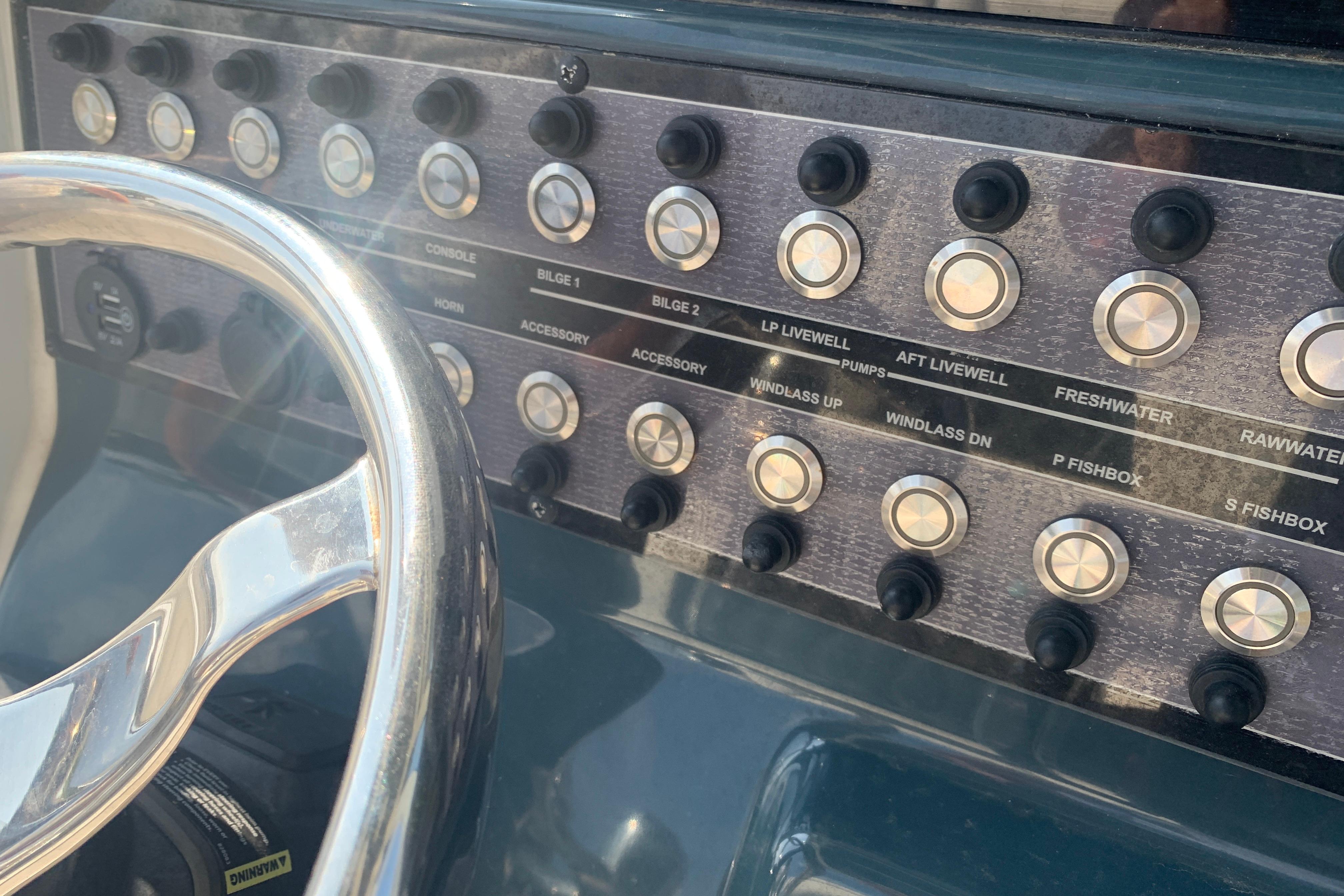 Control panel of 2021 Tidewater 256 CC Adventure boat with steering wheel and switches.