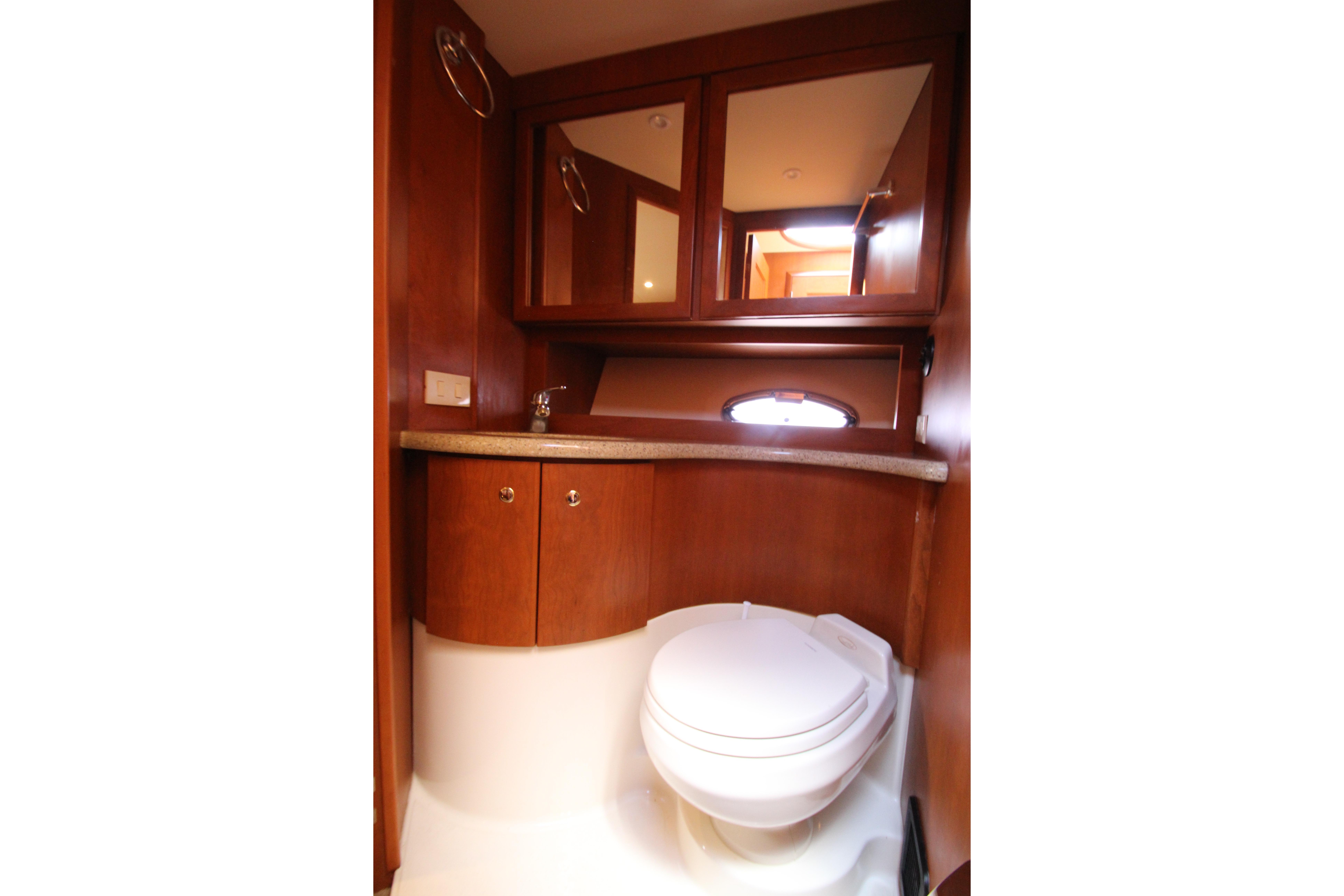 Luxurious bathroom interior of 2006 Silverton 38 Sport Bridge yacht with wooden cabinetry.
