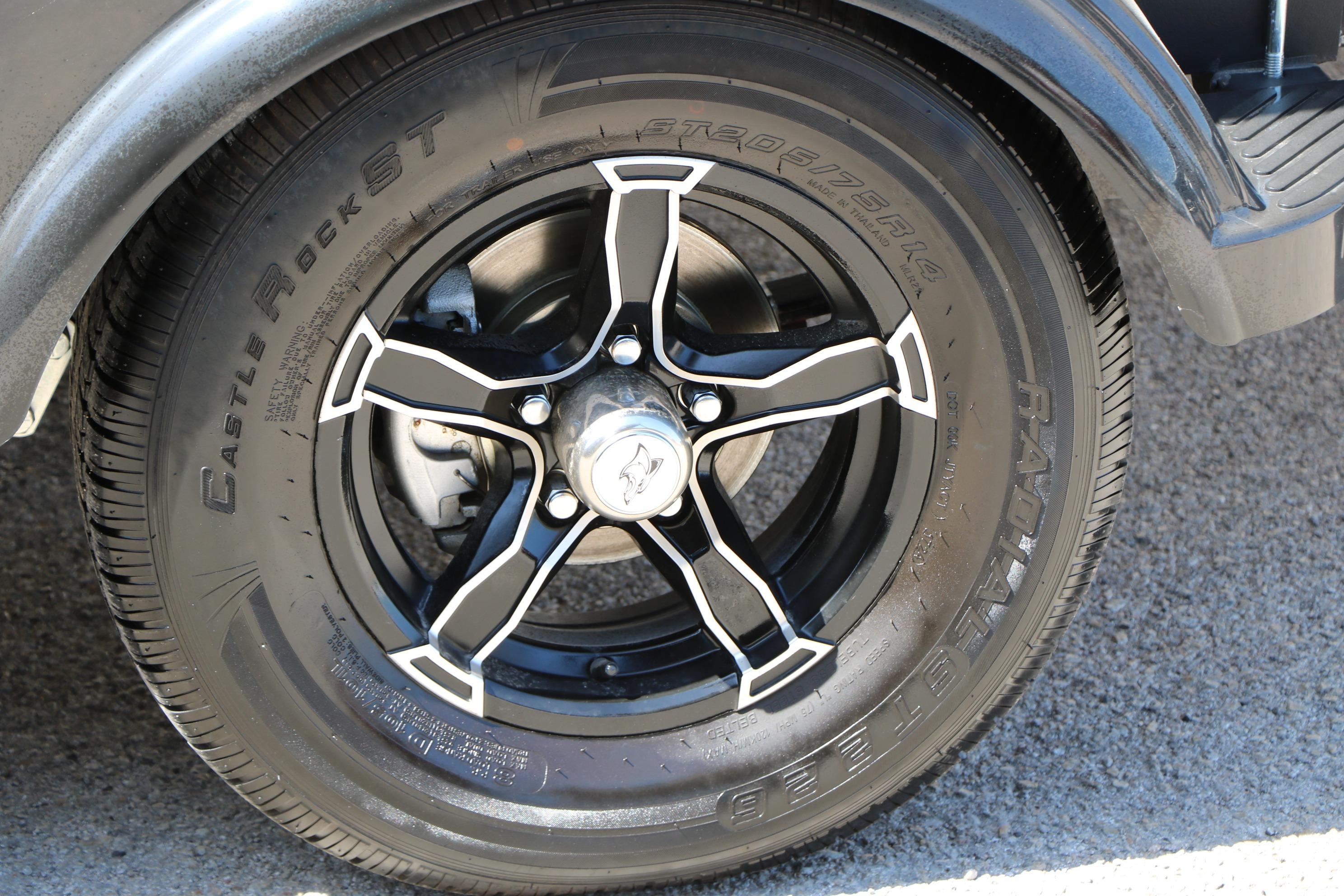 Black alloy wheel and tire of 2025 Chaparral 21 SSi Ski & Fish boat trailer.