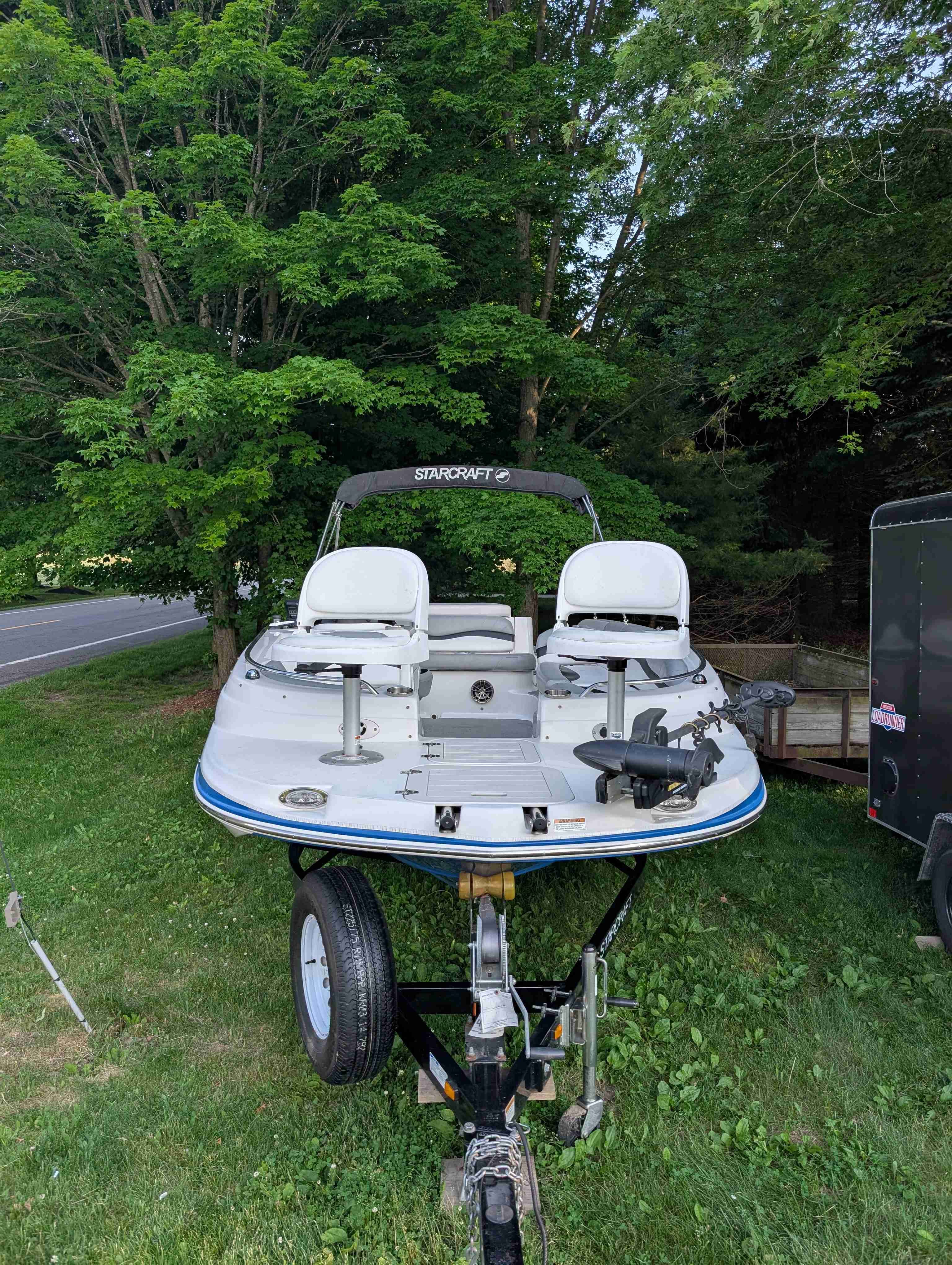 2015 Starcraft 2000 boat on a trailer in a grassy area.