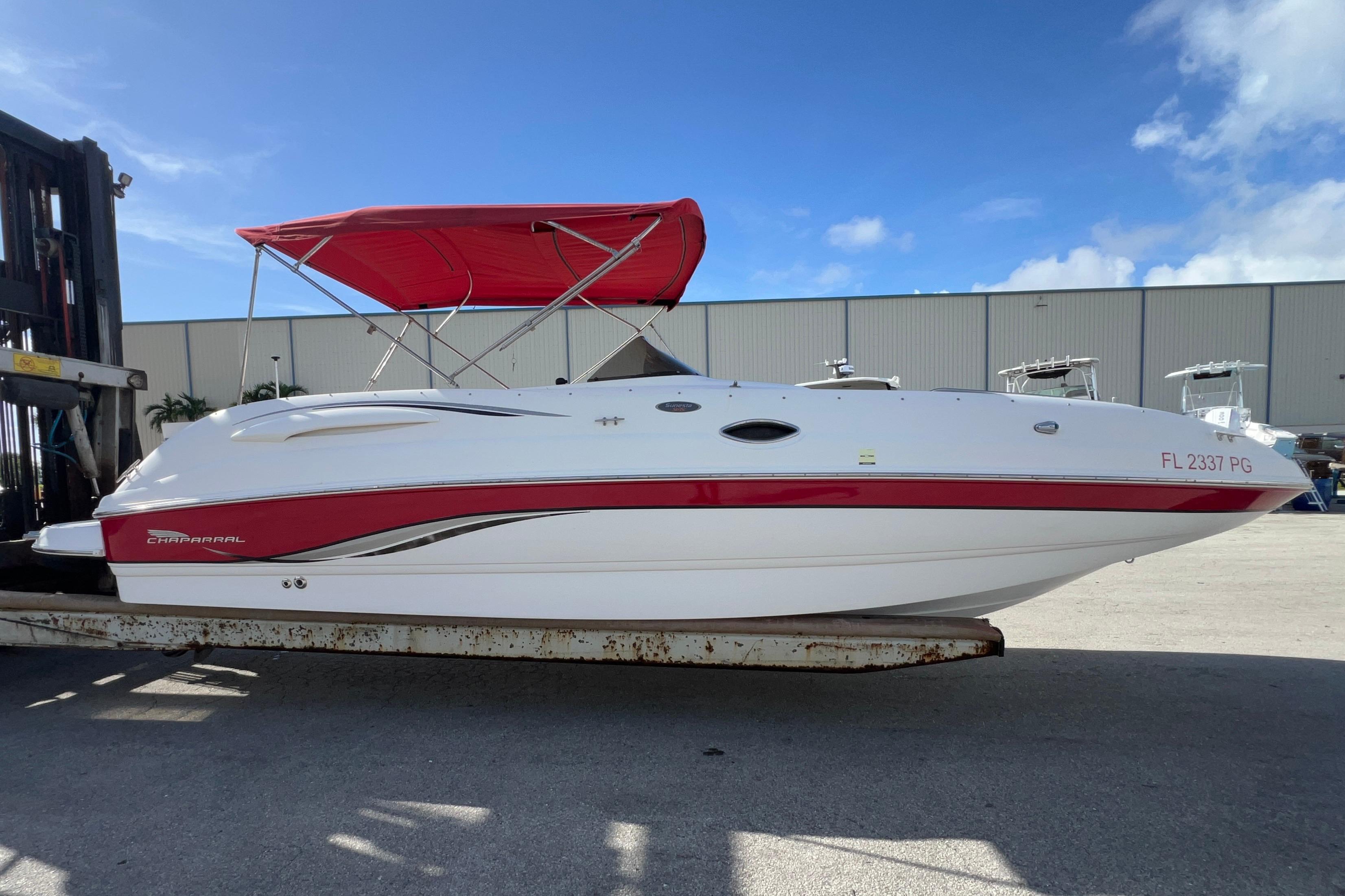 2002 Chaparral 232 Sunesta boat with red canopy on a trailer, under clear blue sky.