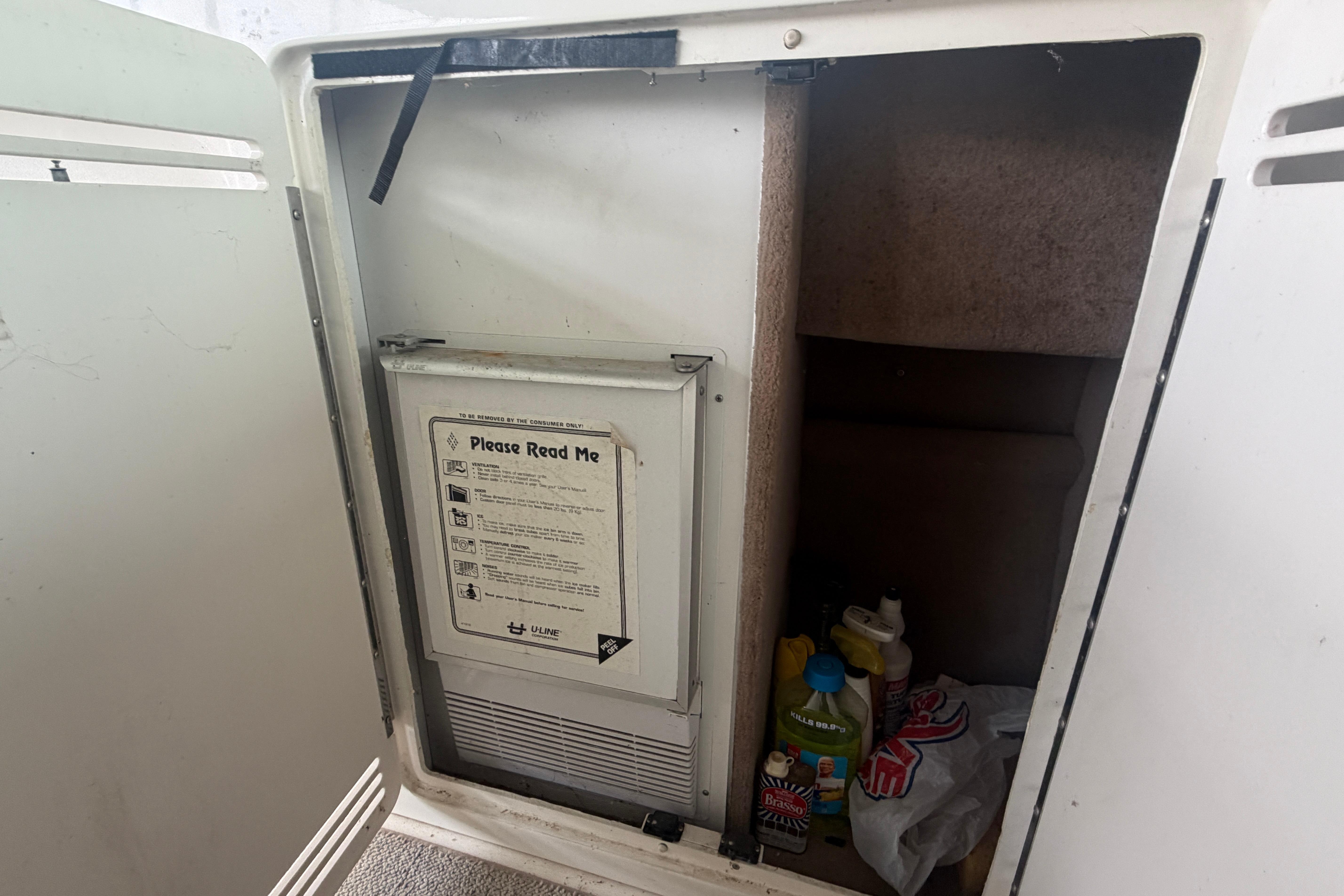 Open cabinet on 1999 Sea Ray 400 Sundancer with cleaning supplies and instructions.