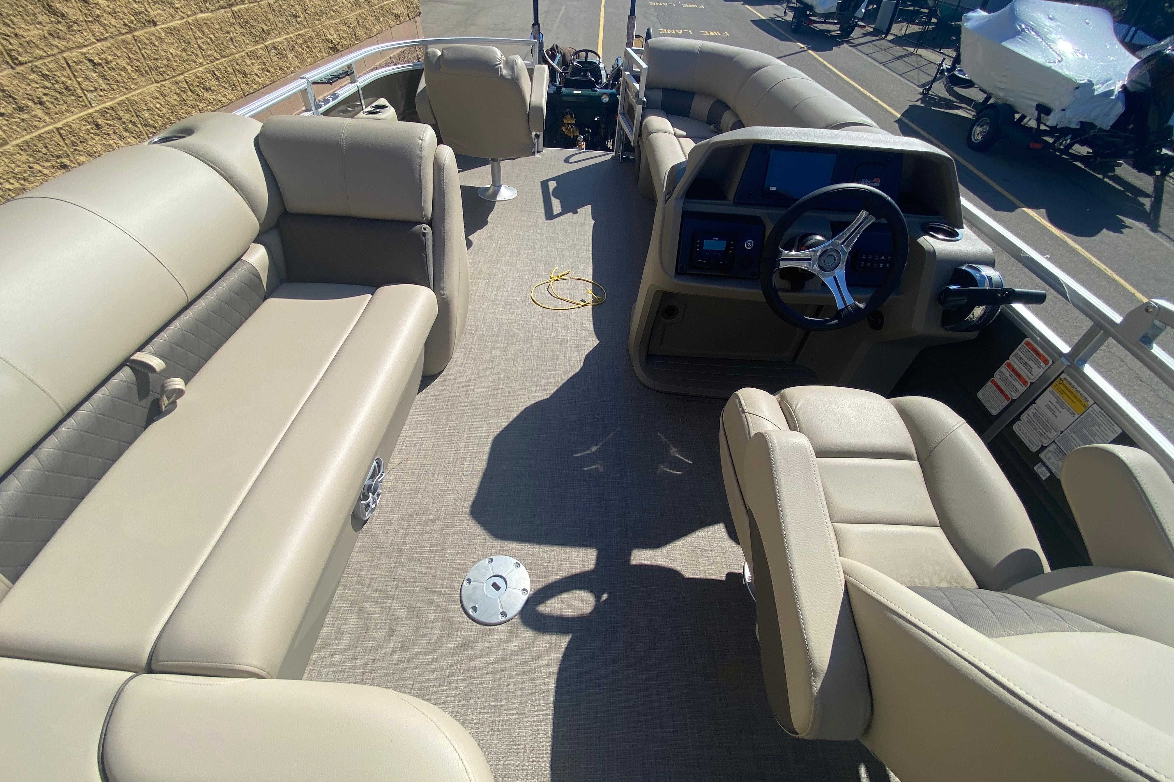 2025 Sun Tracker SportFish 20 DLX pontoon boat interior with beige seating and steering console.