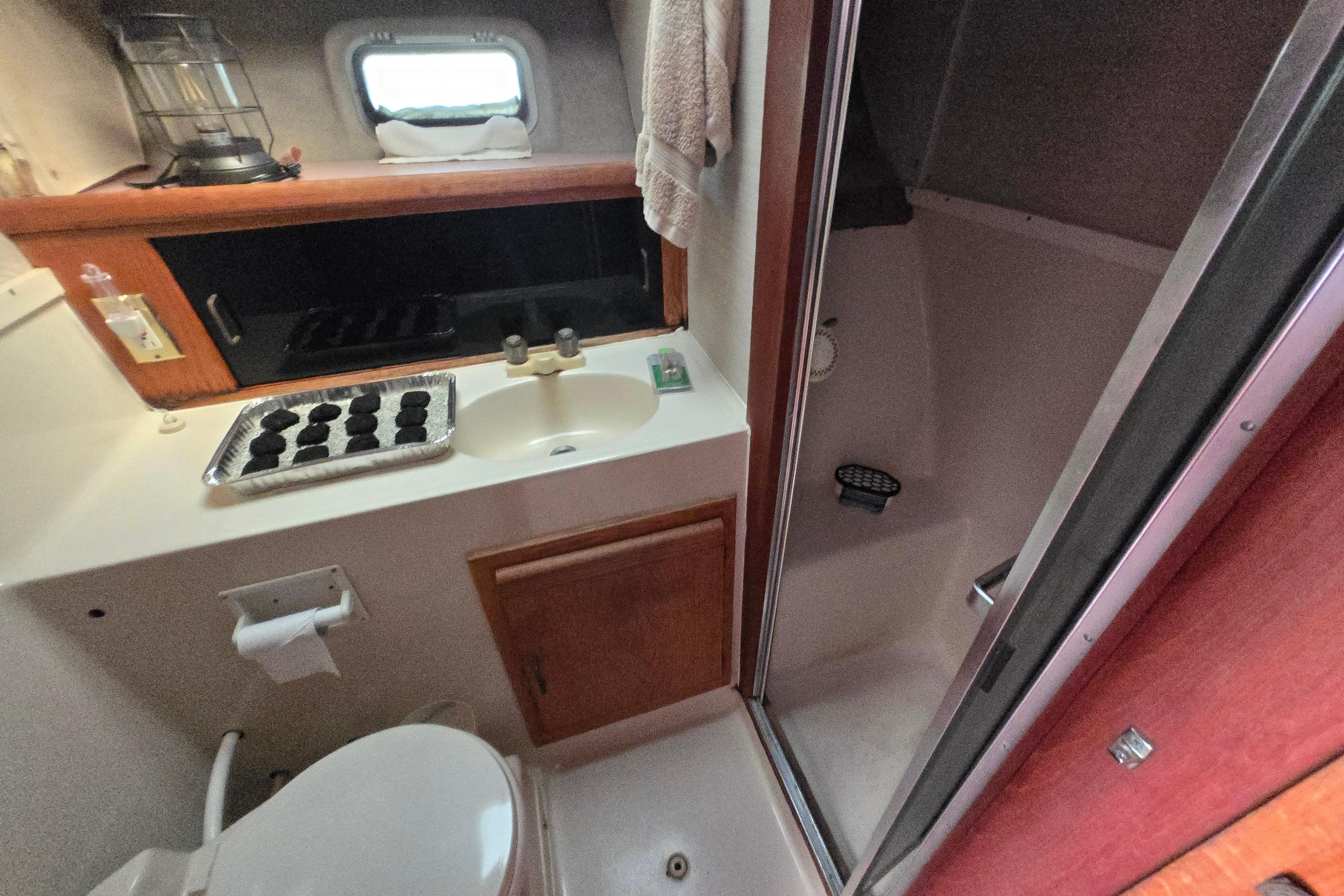 Bathroom interior of 1988 Silverton 34 Convertible yacht with sink, shower, and toilet.