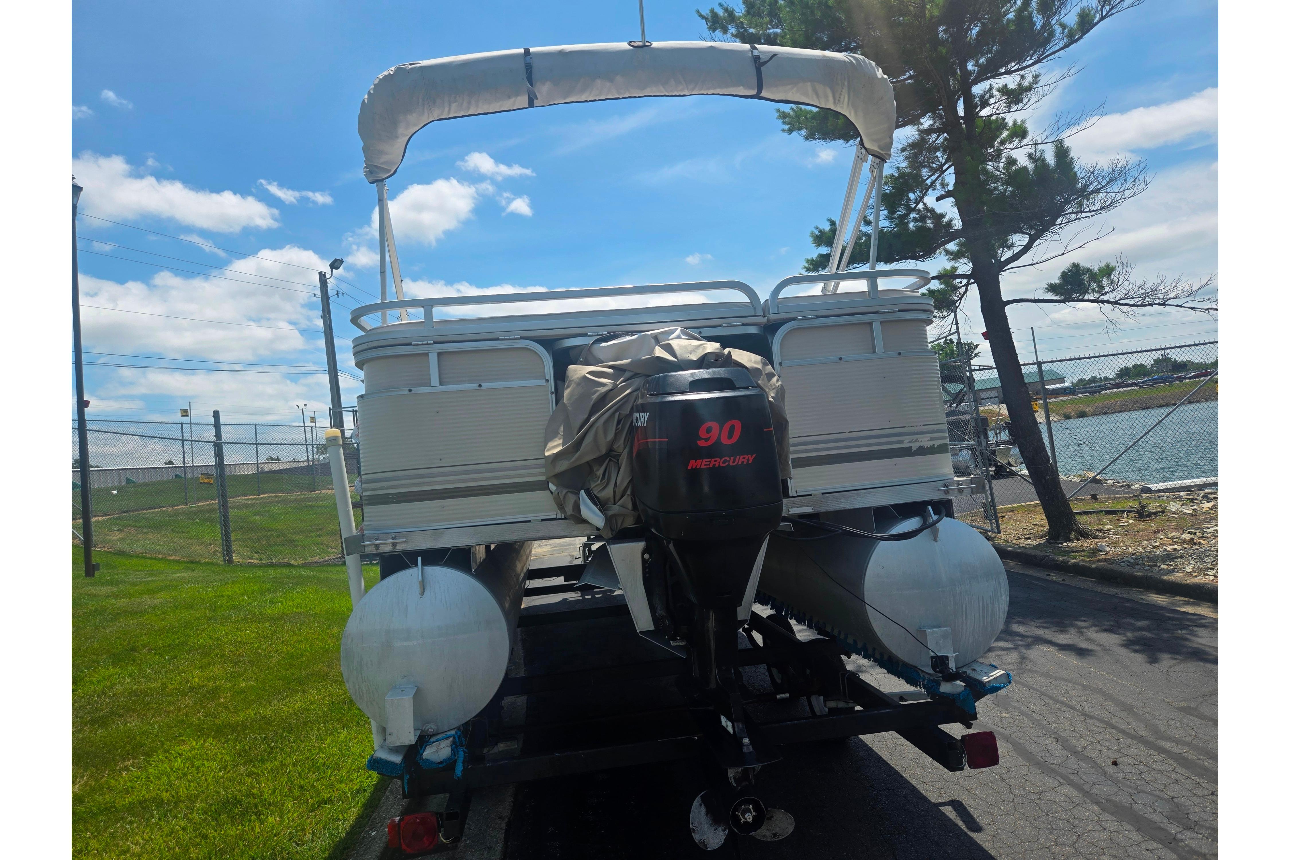 2000 Sylvan 824 Elite Cruise pontoon boat with Mercury 90 engine, parked near water.