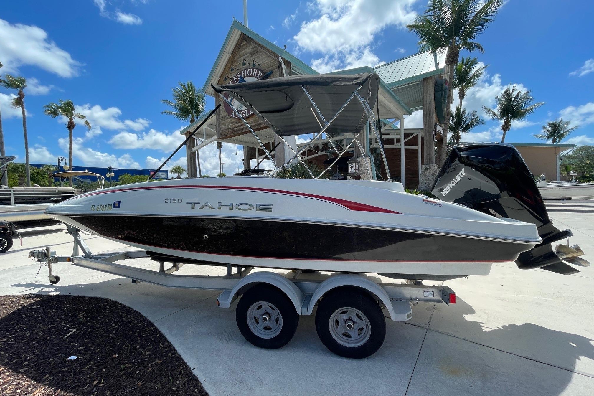 2024 Tahoe 2150 OB boat on trailer, parked near palm trees under a clear blue sky.