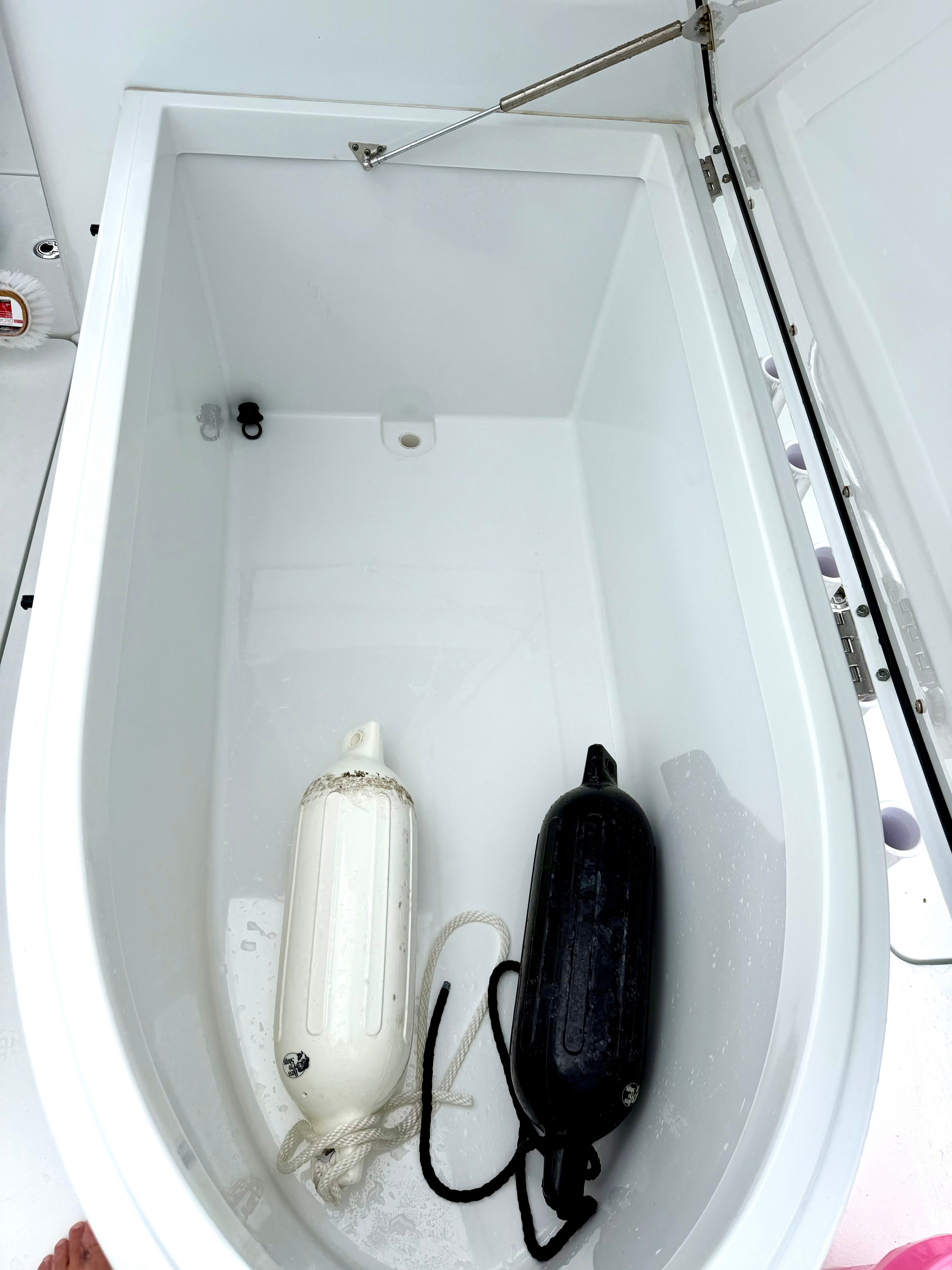 An open storage compartment with two fenders, one white and one black, inside.