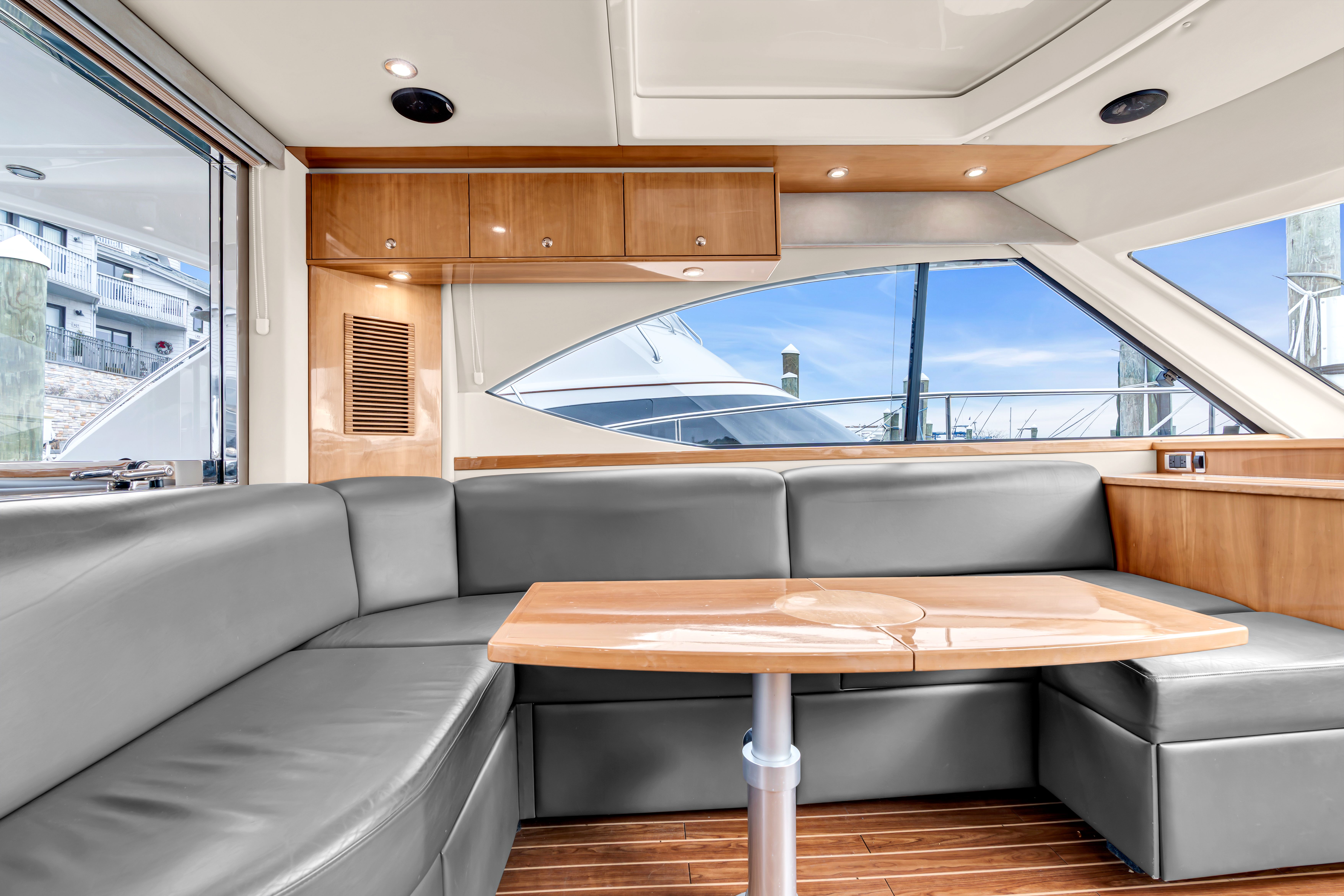 Interior of 2014 Riviera 44 Sport Yacht with gray seating and wooden table.