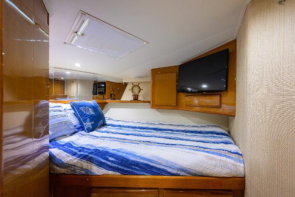 Luxurious cabin interior of 2000 Viking 50 Convertible yacht with cozy bedding and TV.