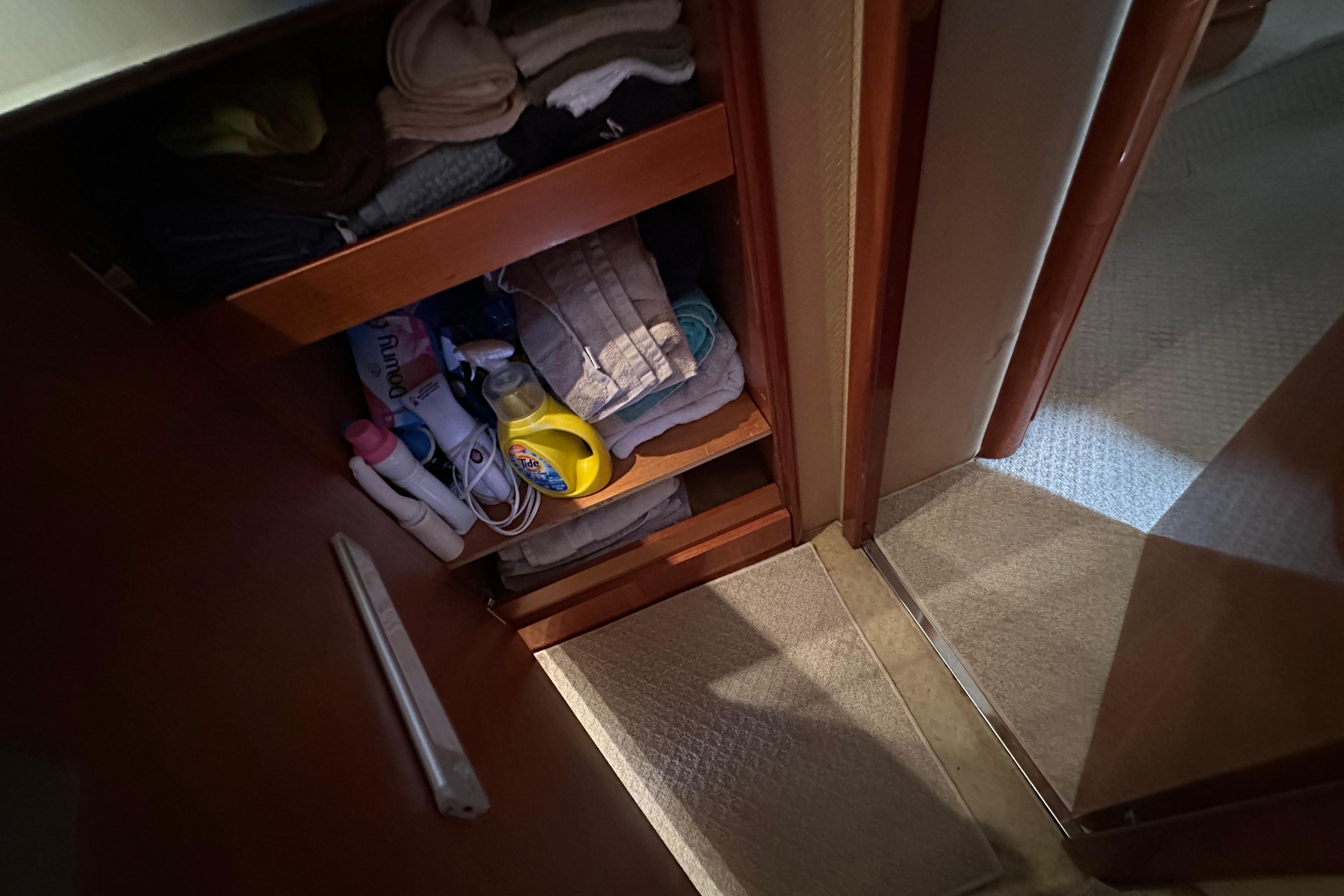 Storage shelves with cleaning supplies and towels on a 2004 Azimut 55E yacht.