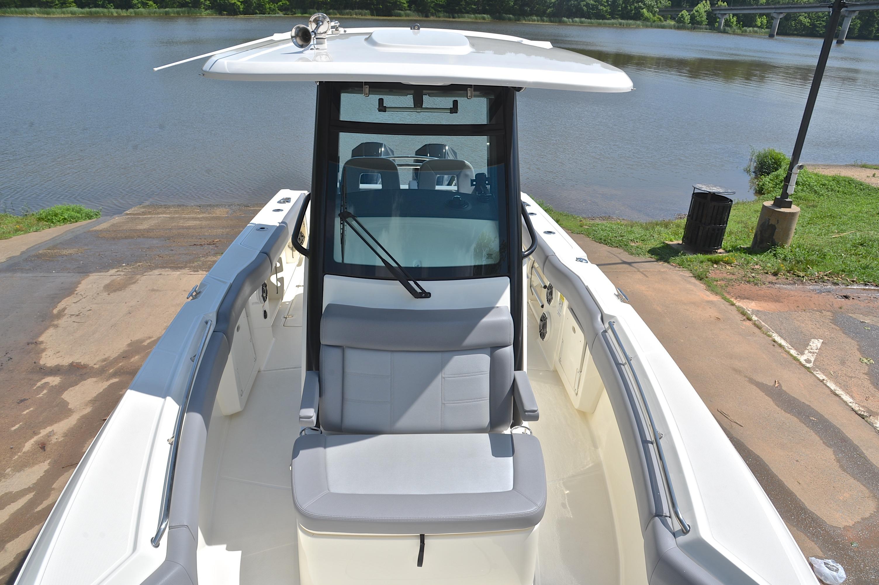 2024 Boston Whaler 250 Outrage boat at a lakeside dock, showcasing seating and helm.