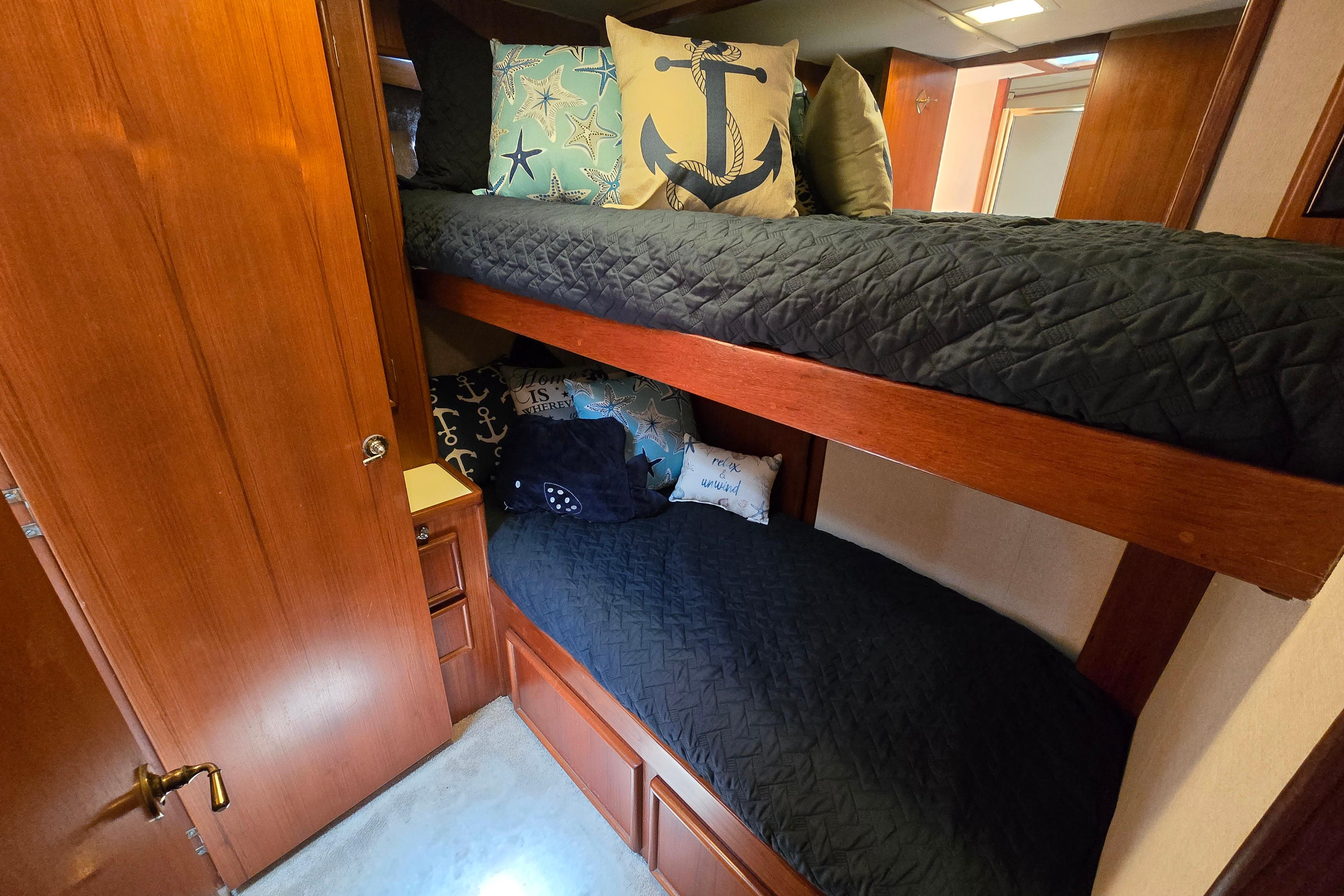 Cozy bunk beds with nautical-themed pillows in a 1988 Post 46 Convertible yacht cabin.