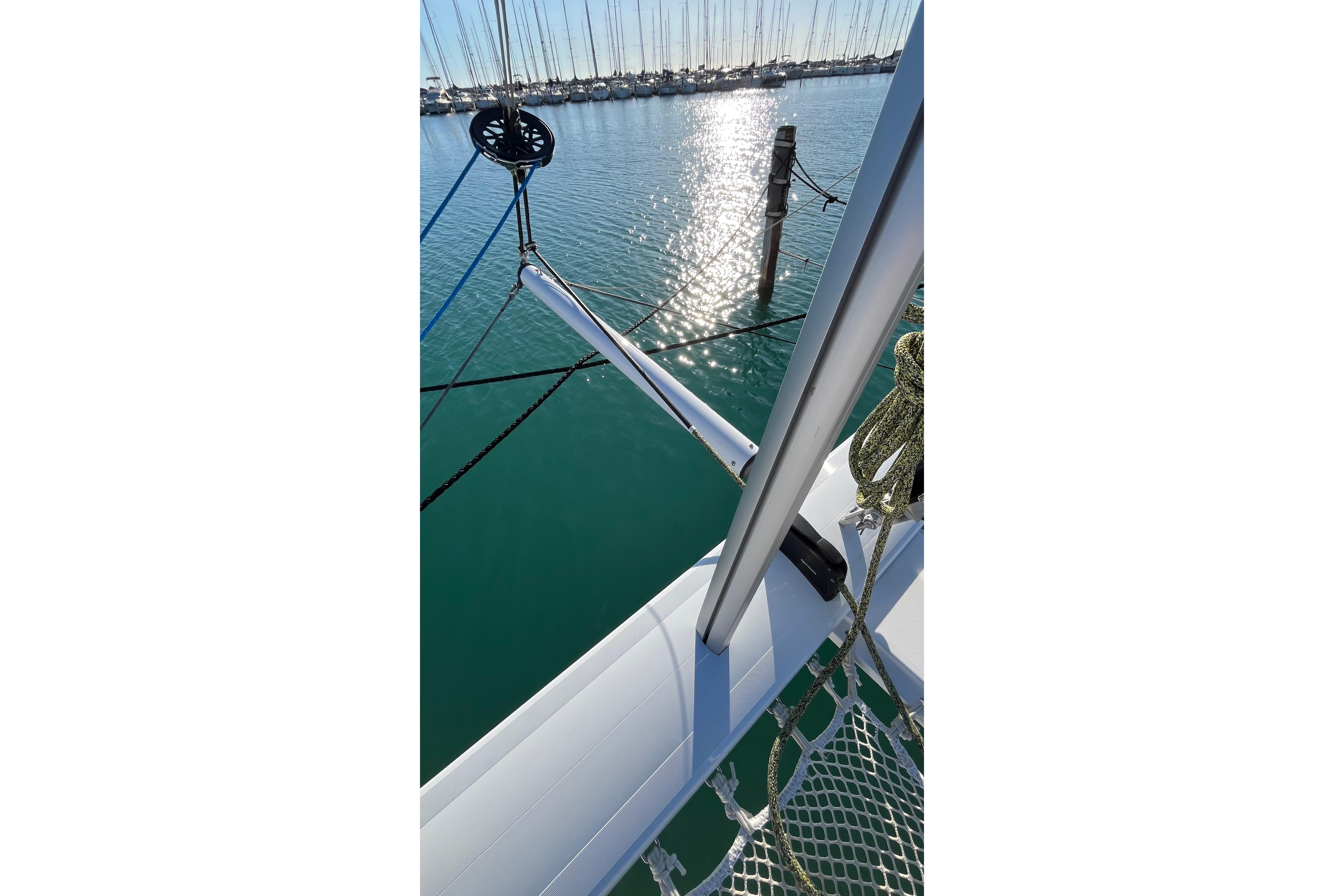2024 Outremer 45 catamaran deck with netting, reflecting sunlight on calm water.