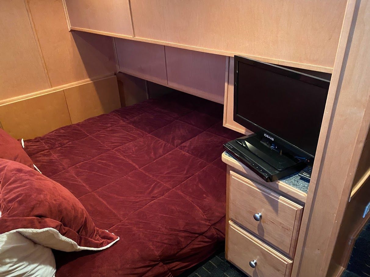 Bedroom in Summersun Houseboat 16x68, 2006 model, with TV and red bedding.