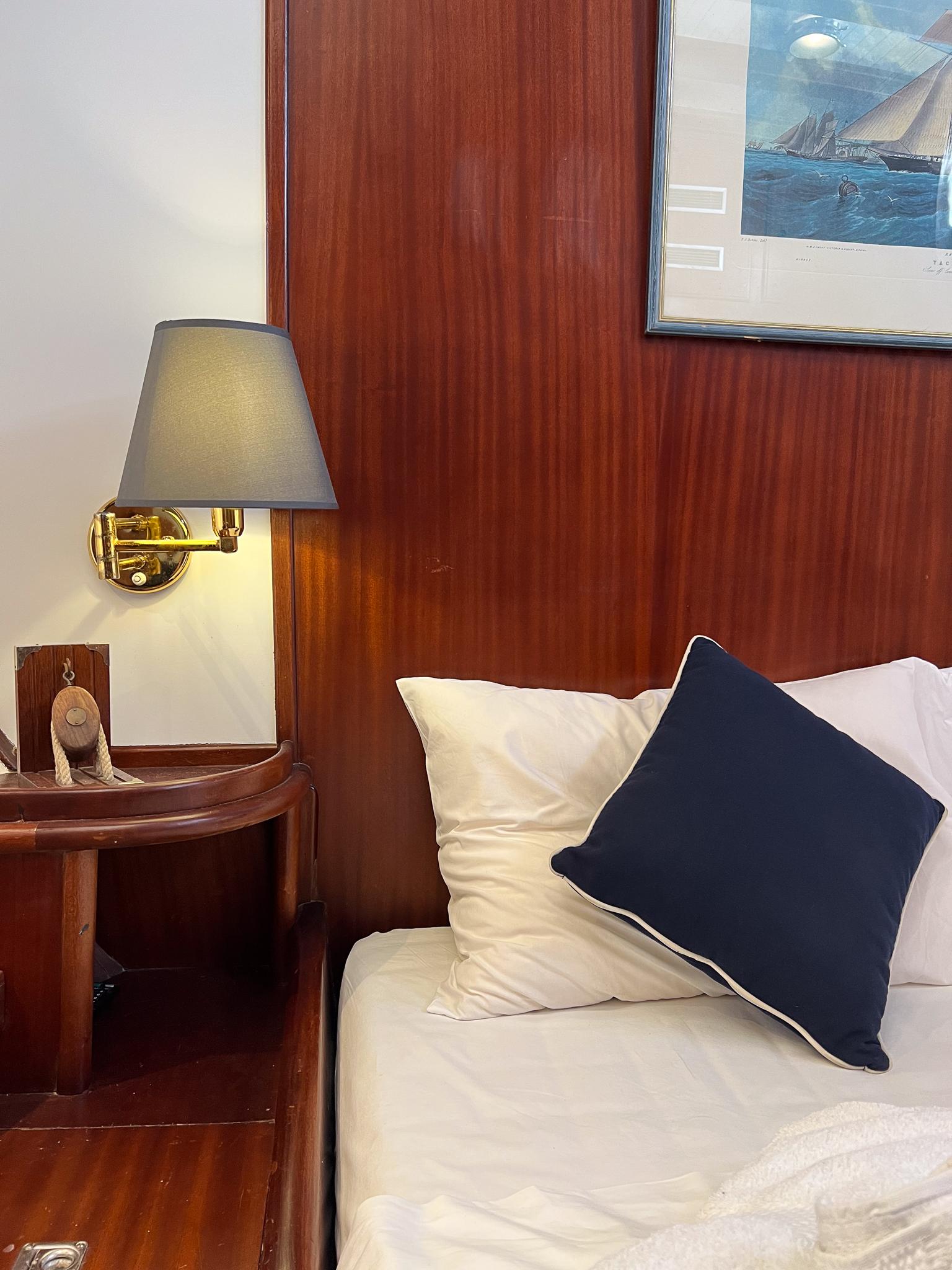 Cozy ship cabin with wooden paneling, bed, and nautical decor, Psarros Shipyard 1969.