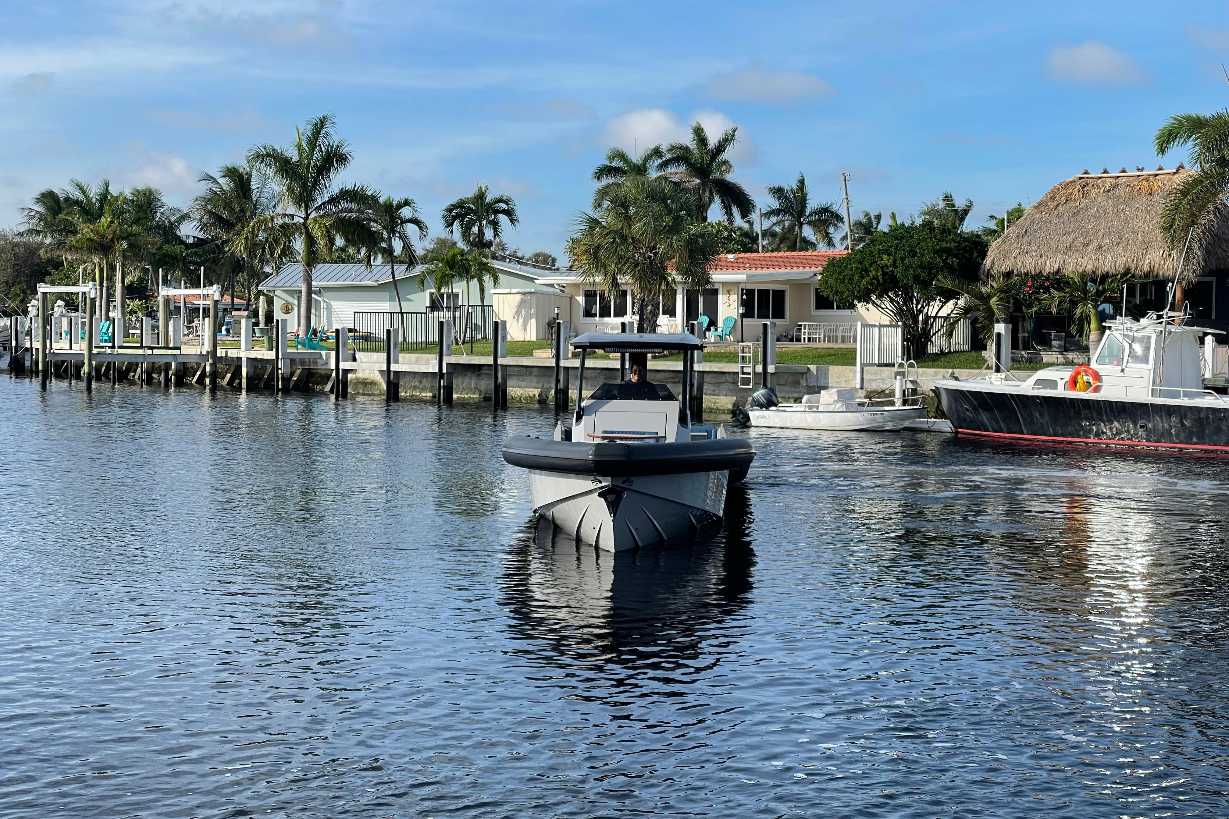 2023 Skipper-BSK BSK 38 boat cruising near waterfront homes and palm trees.